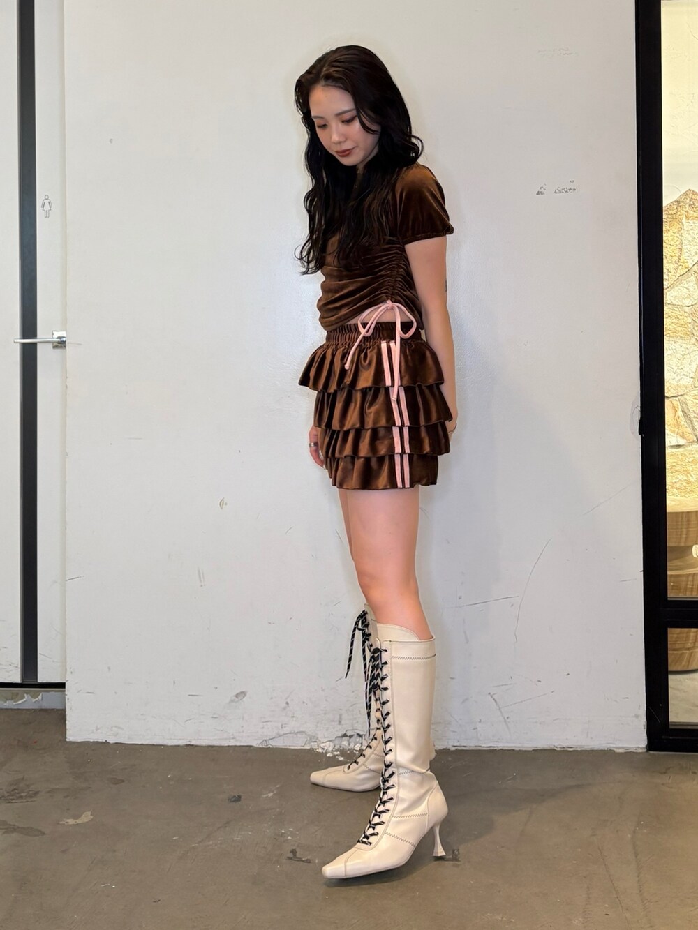 ブラウン系のスカート、ブラウン系のTシャツ/カットソー、ホワイト系のブーツを着用したレディースの夏コーディネートの2枚目の写真