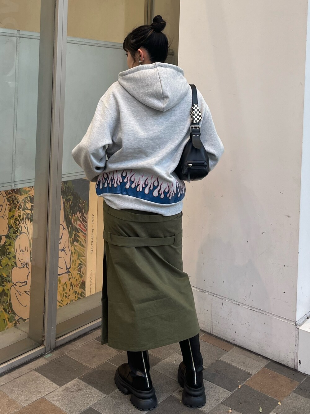 グリーン系のスカート、グレー系のパーカー、ブラック系のブーツを着用したレディースの冬コーディネートの3枚目の写真