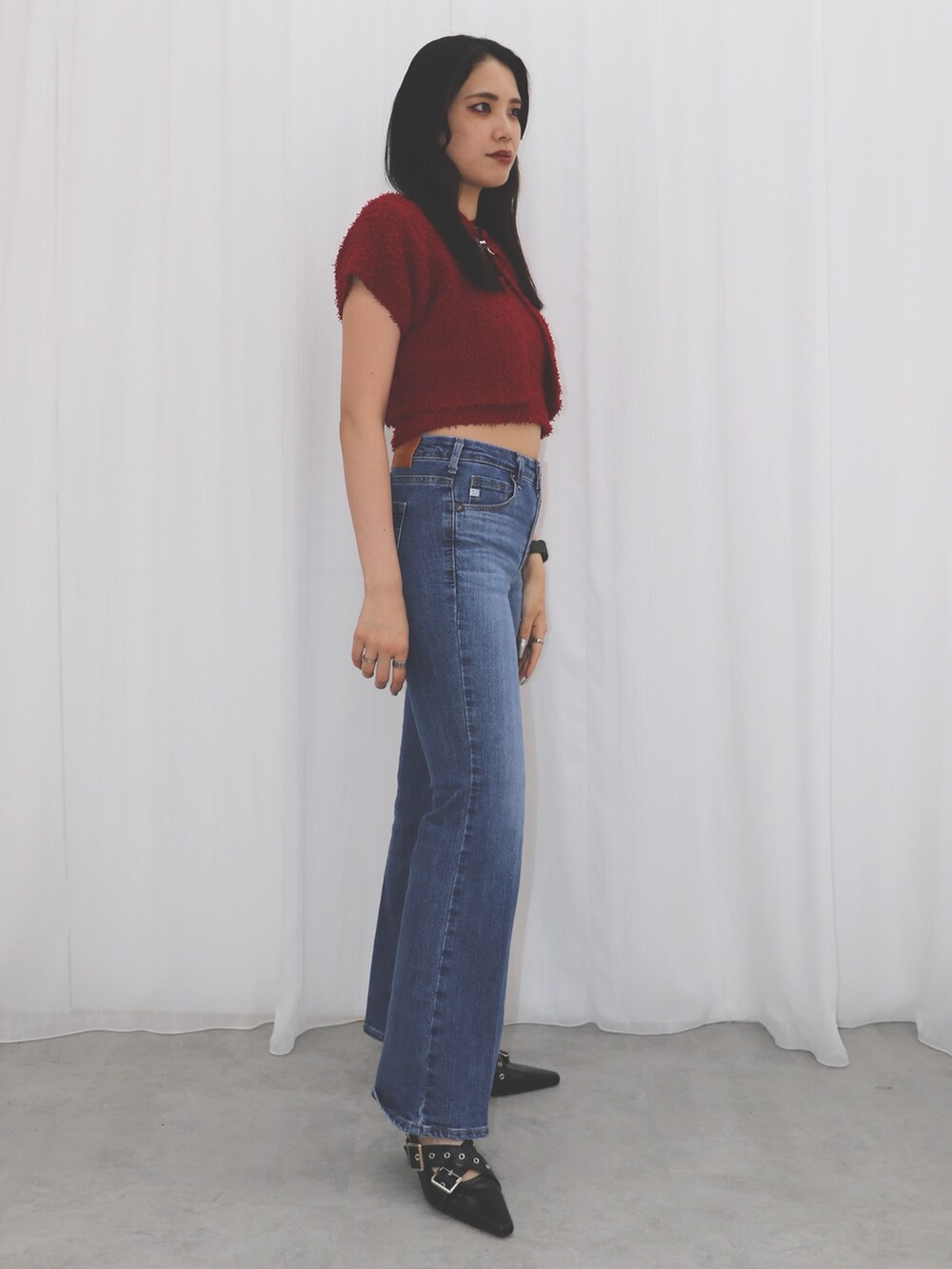 ブルー系のデニムパンツ、レッド系のアンサンブル、ブラック系のパンプスを着用したレディースの夏コーディネートの3枚目の写真