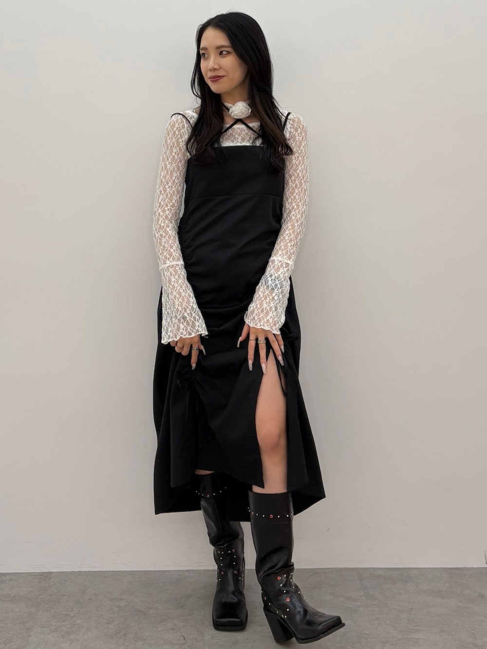 ブラック系のワンピース、ホワイト系のTシャツ/カットソー、ブラック系のブーツを着用したレディースの春コーディネートの2枚目の写真