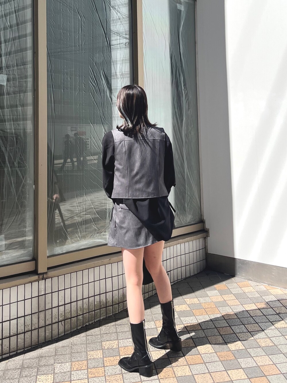 ブラック系のシャツ/ブラウス、グレー系のベスト、ブラック系のブーツを着用したレディースの春コーディネートの2枚目の写真