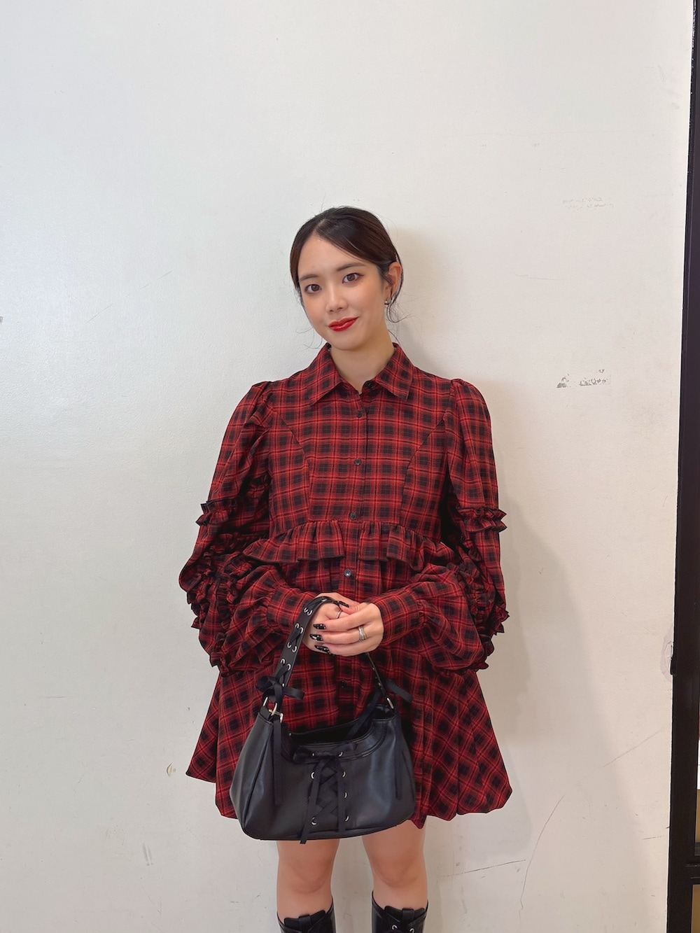 レッド系のワンピース、ブラック系のハンドバッグ、ブラック系のブーツを着用したレディースの秋コーディネートの3枚目の写真