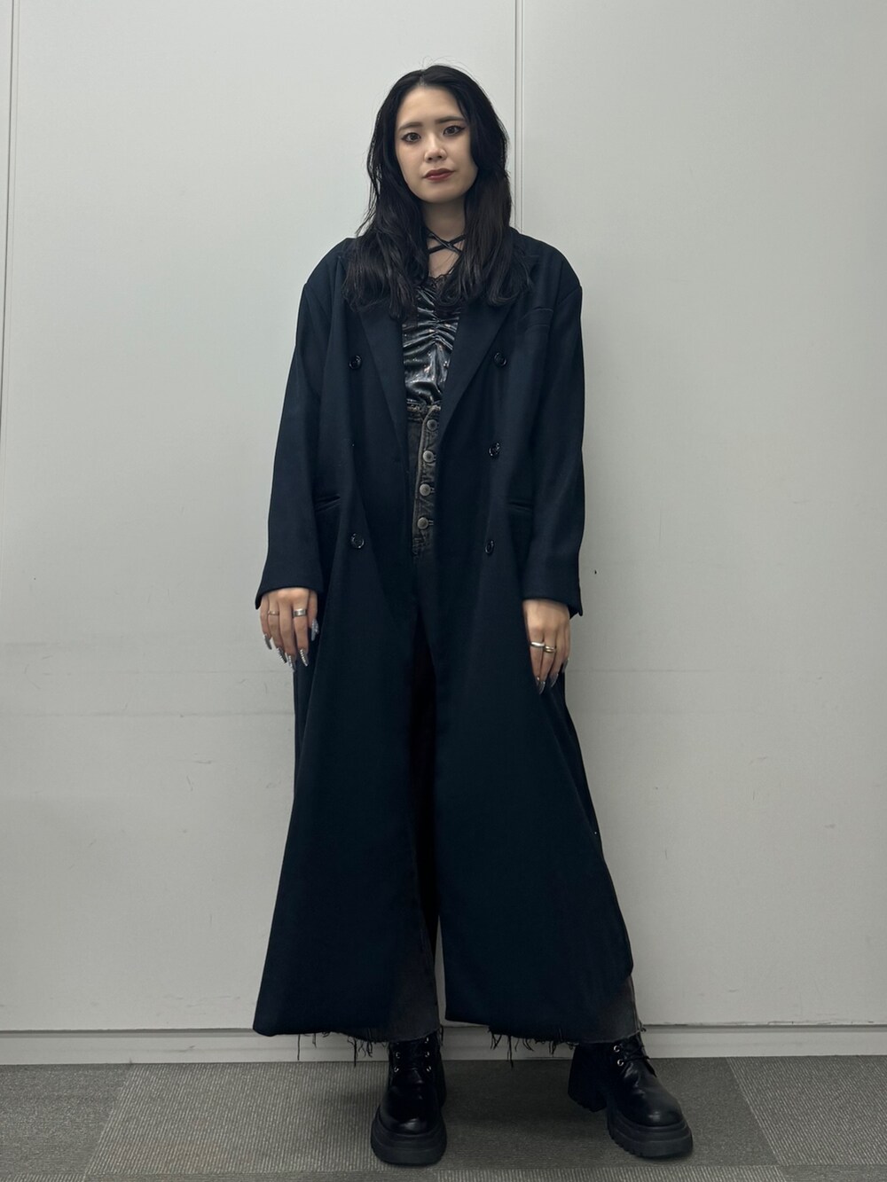 グレー系のワンピース、ブルー系のチェスターコート、ブラック系のデニムパンツを着用したレディースの秋コーディネートの2枚目の写真