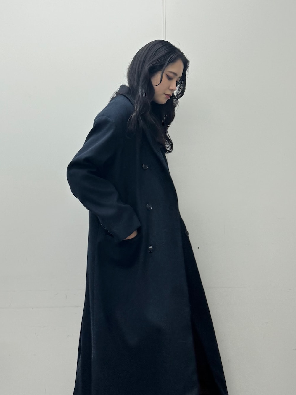 グレー系のワンピース、ブルー系のチェスターコート、ブラック系のデニムパンツを着用したレディースの秋コーディネートの5枚目の写真