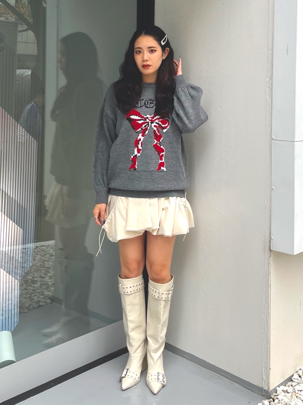 グレー系のニット/セーター、ホワイト系のスカート、ホワイト系のブーツを着用したレディースの冬コーディネートの2枚目の写真