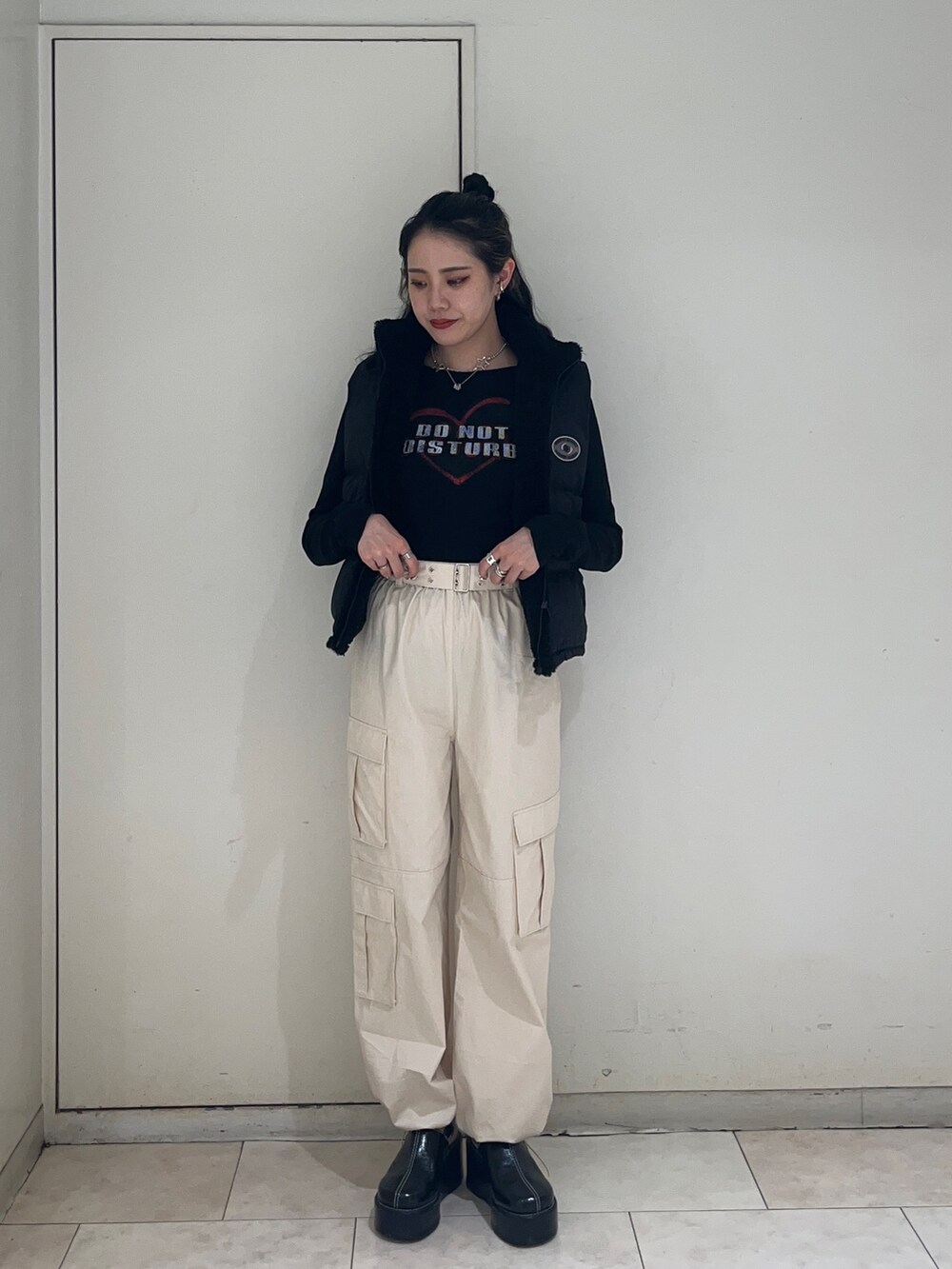 ブラック系のダウンベスト、ホワイト系のカーゴパンツ、ブラック系のTシャツ/カットソーを着用したレディースの秋コーディネートの2枚目の写真