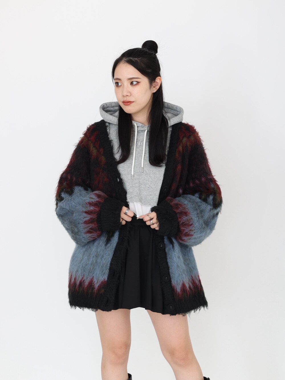 ブラック系のカーディガン/ボレロ、グレー系のパーカー、ブラック系のスカートを着用したレディースの秋コーディネートの5枚目の写真