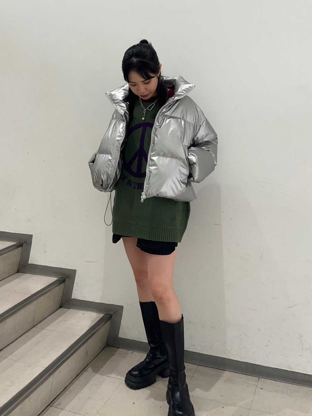 シルバー系のダウンジャケット/コート、グリーン系のニット/セーター、ブラック系のその他パンツを着用したレディースの冬コーディネートの3枚目の写真