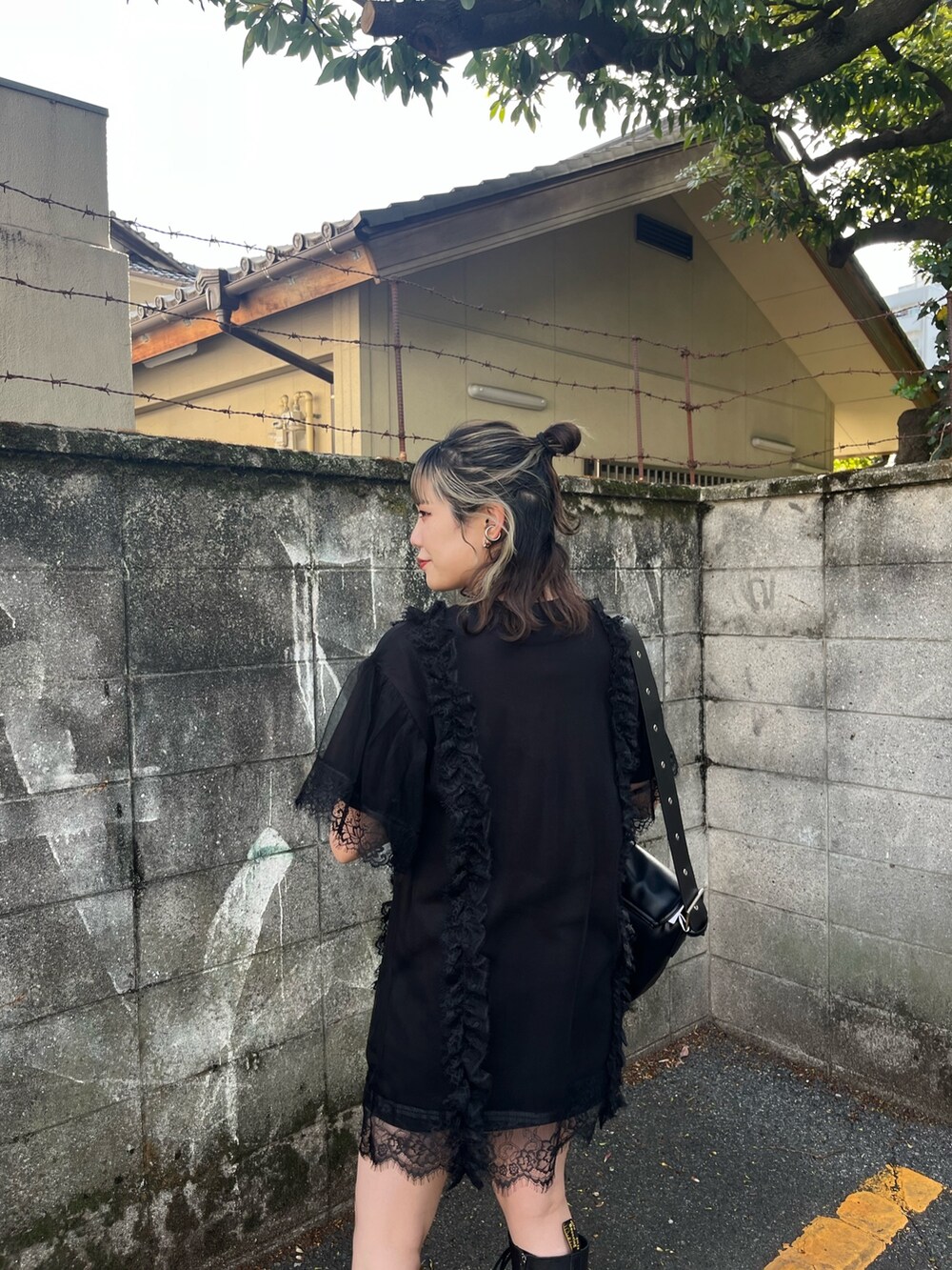 ブラック系のワンピース、ブラック系のメッセンジャーバッグ、ブラック系のブーツを着用したレディースの春コーディネートの6枚目の写真