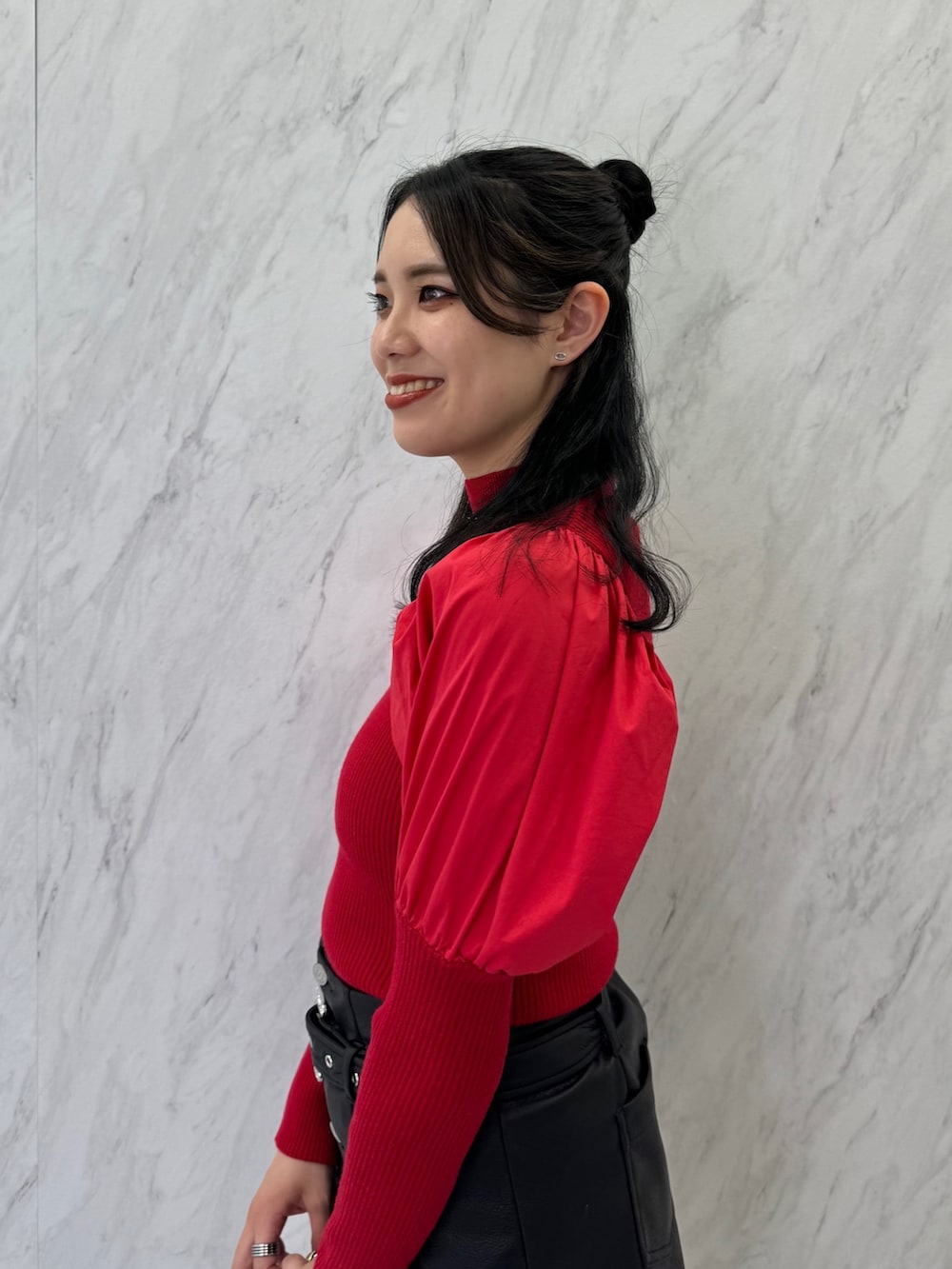 レッド系のニット/セーター、ブラック系のスカート、ブラック系のブーツを着用したレディースの夏コーディネートの4枚目の写真