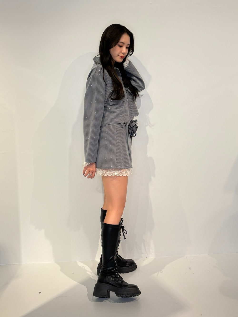 グレー系のテーラードジャケット、グレー系のスカート、ブラック系のブーツを着用したレディースの秋コーディネートの2枚目の写真