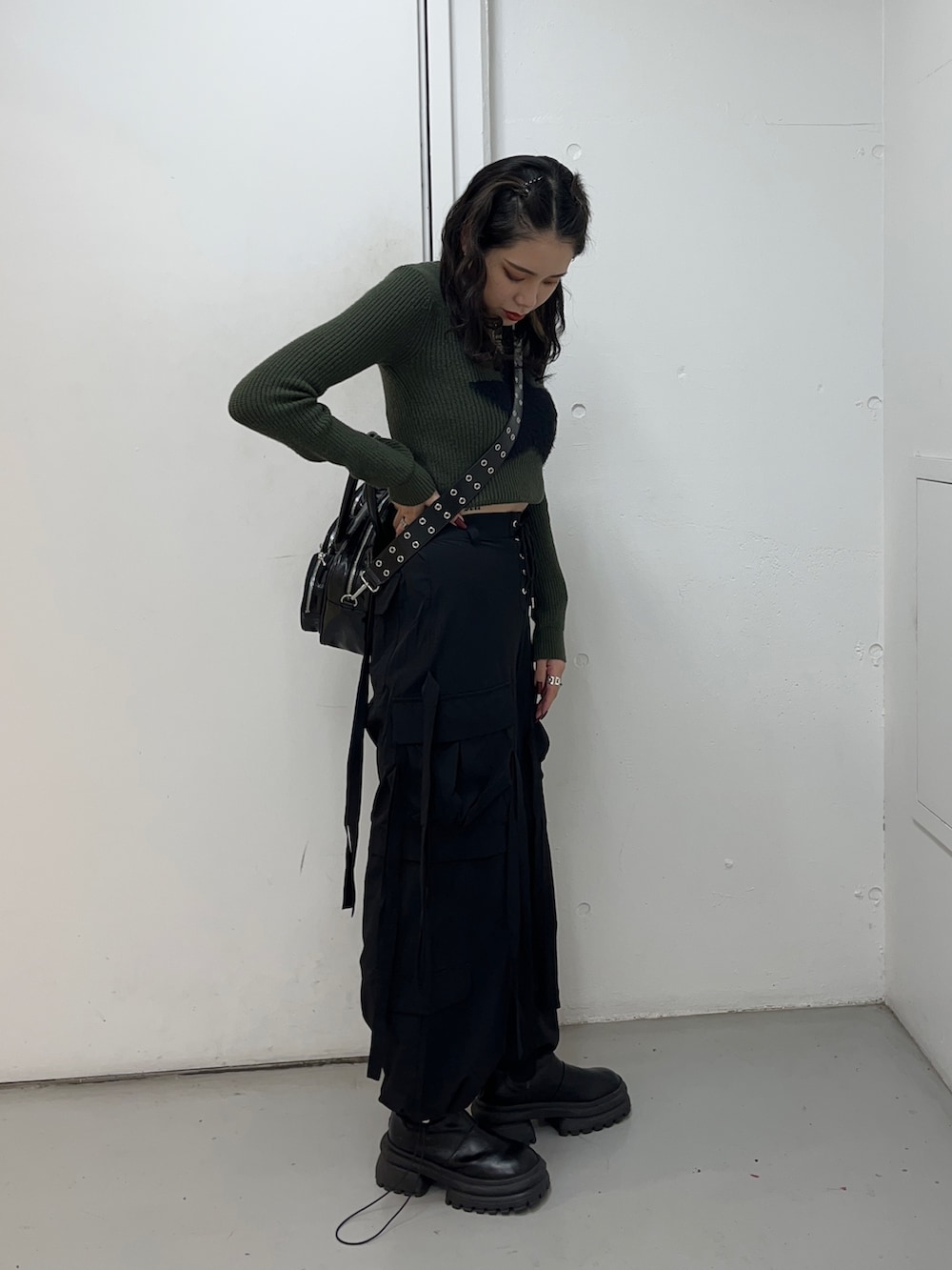 グリーン系のニット/セーター、ブラック系のその他パンツ、ブラック系のボストンバッグを着用したレディースの冬コーディネートの3枚目の写真