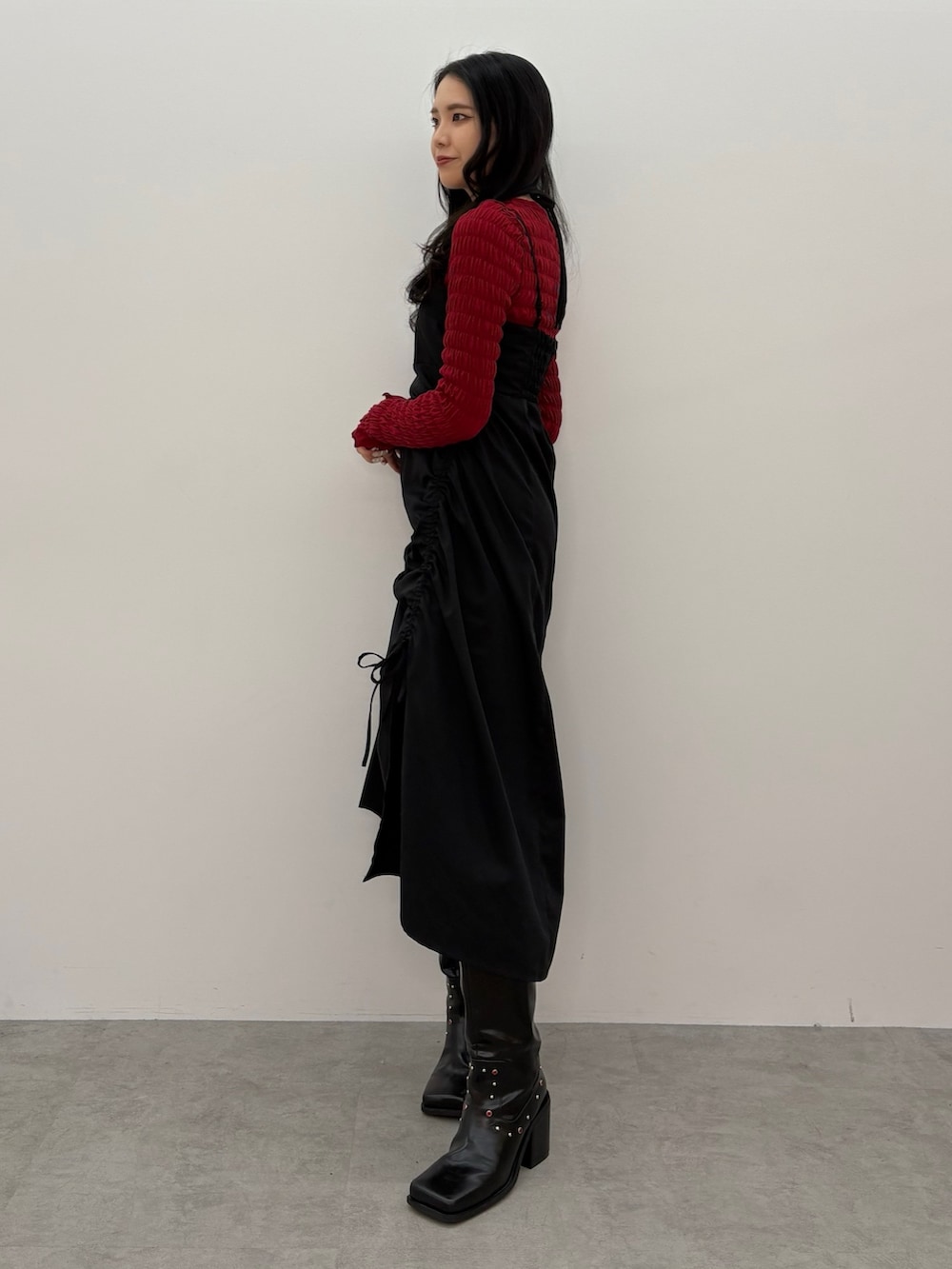 ブラック系のワンピース、レッド系のTシャツ/カットソー、ブラック系のブーツを着用したレディースの春コーディネートの2枚目の写真