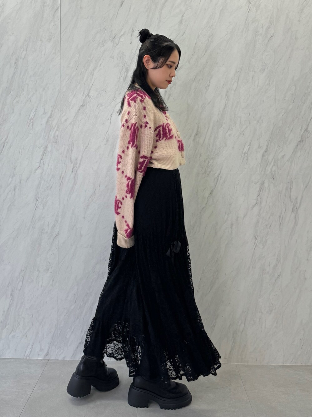 ホワイト系のカーディガン/ボレロ、ブラック系のスカート、ブラック系のブーツを着用したレディースの夏コーディネートの3枚目の写真