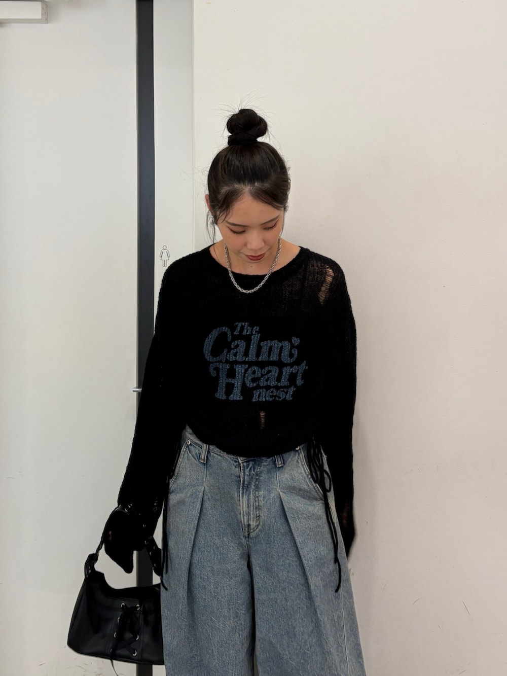 ブラック系のニット/セーター、ブルー系のデニムパンツ、ブラック系のハンドバッグを着用したレディースの秋コーディネートの4枚目の写真