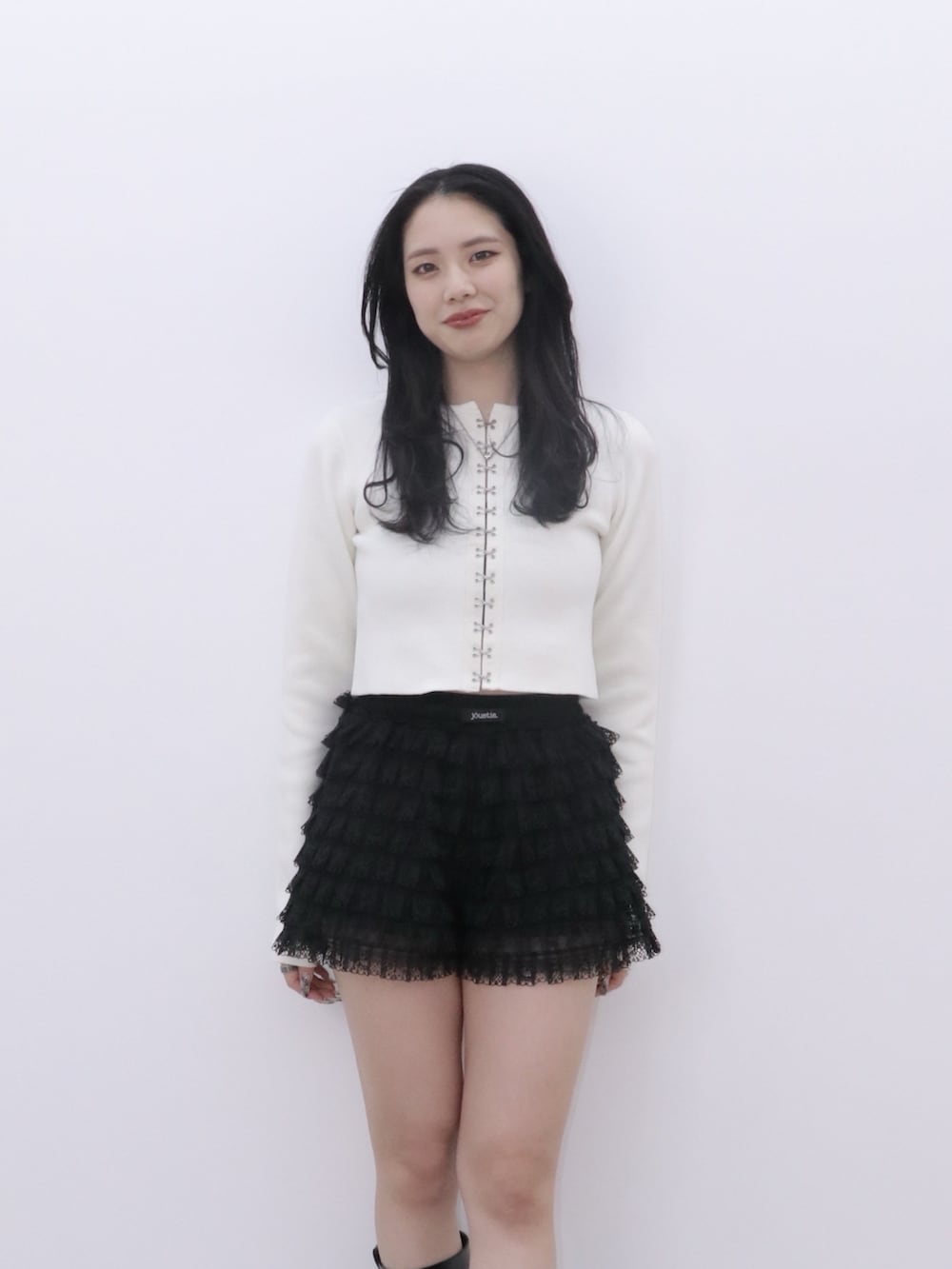 ブラック系のその他パンツ、ホワイト系のカーディガン/ボレロ、ブラック系のブーツを着用したレディースの冬コーディネートの3枚目の写真