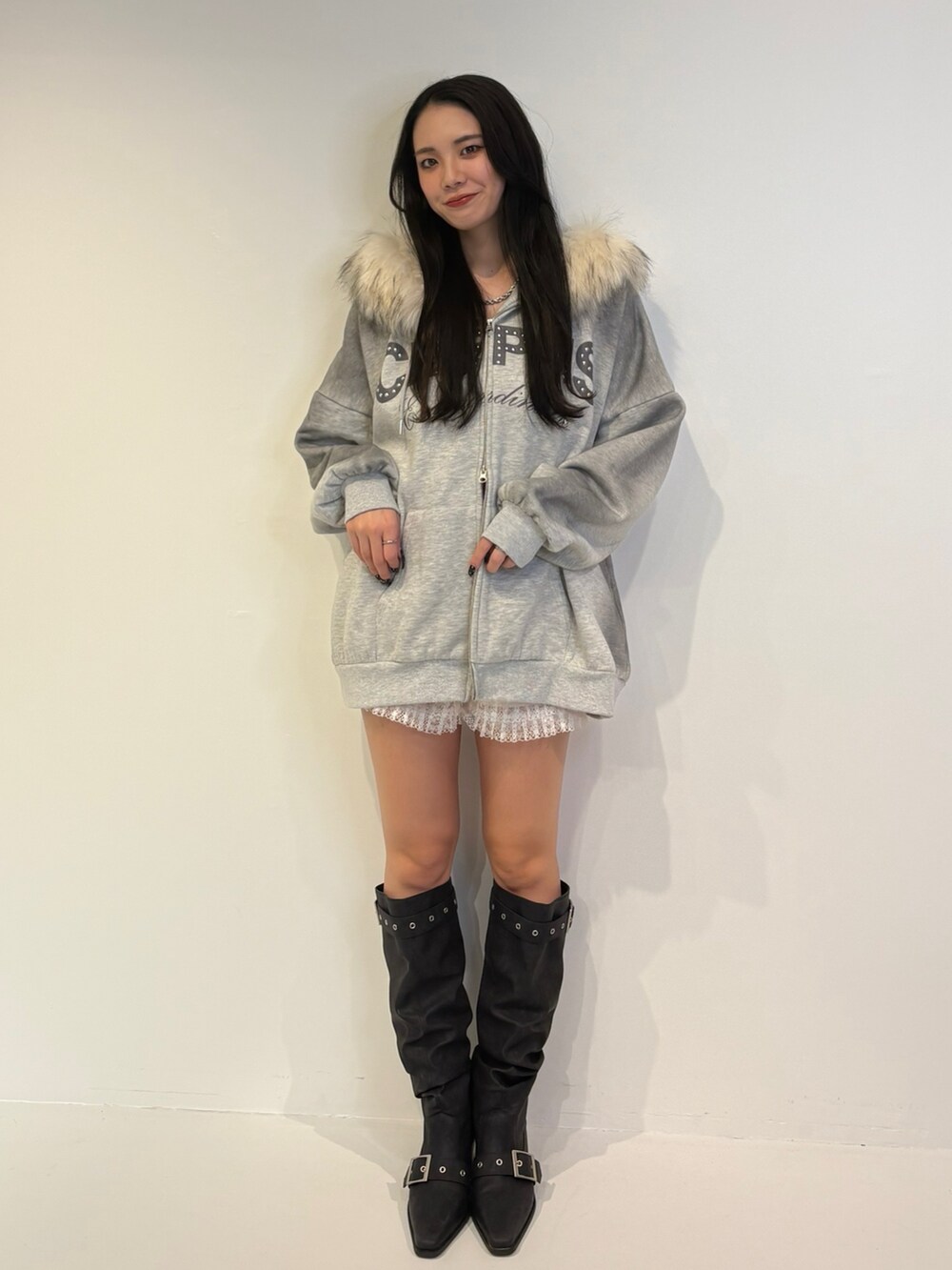 グレー系のパーカー、ブラック系のブーツを着用したレディースの秋コーディネートの2枚目の写真
