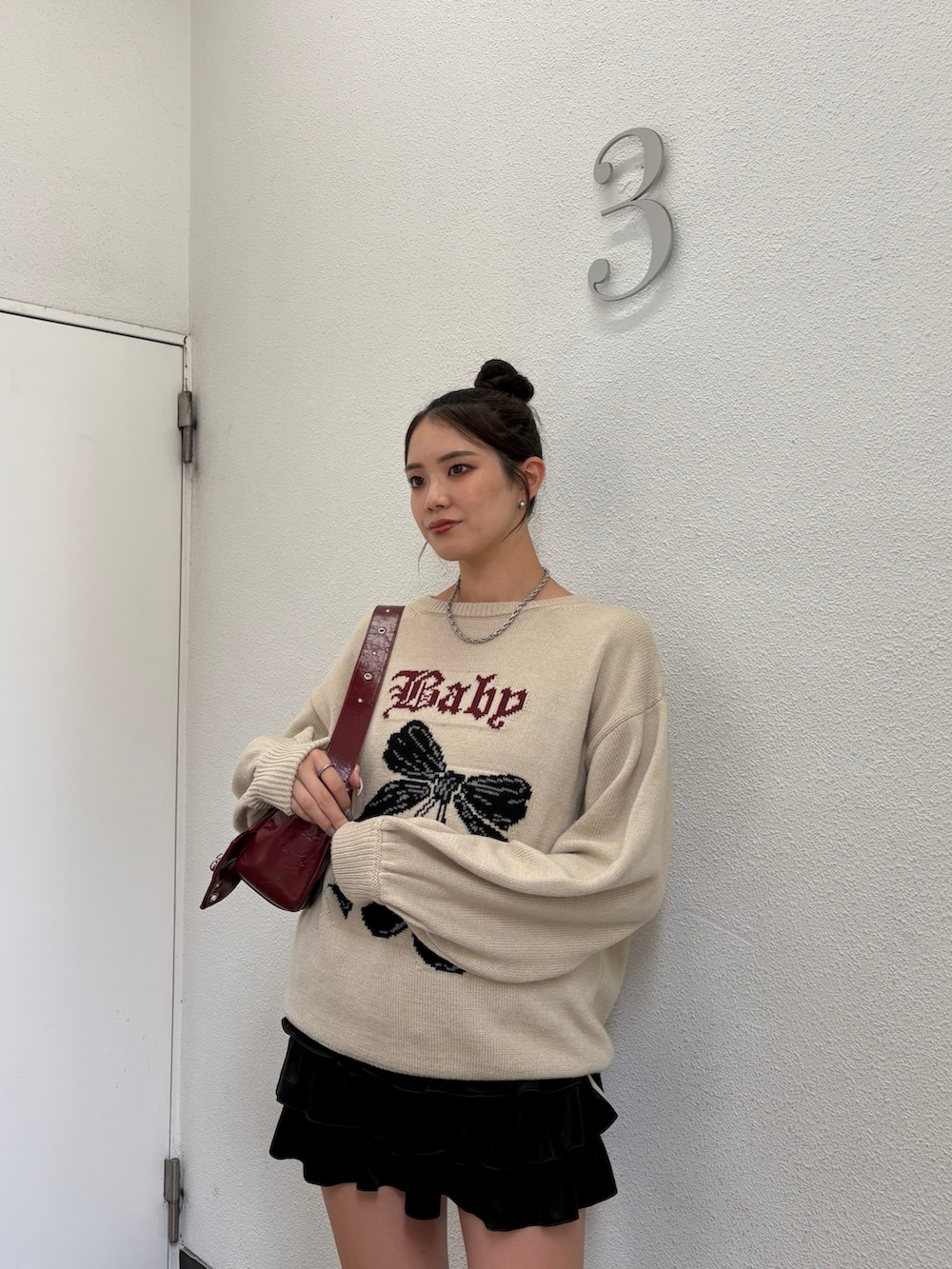 ホワイト系のニット/セーター、ブラック系のスカート、ブラック系のブーツを着用したレディースの秋コーディネートの4枚目の写真