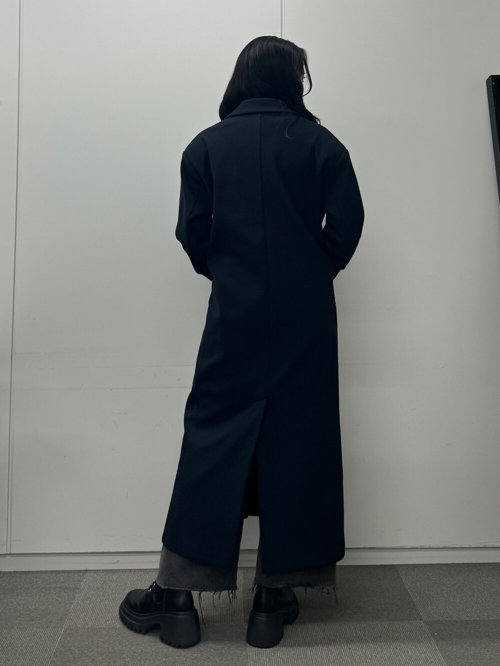 グレー系のワンピース、ブルー系のチェスターコート、ブラック系のデニムパンツを着用したレディースの秋コーディネートの4枚目の写真