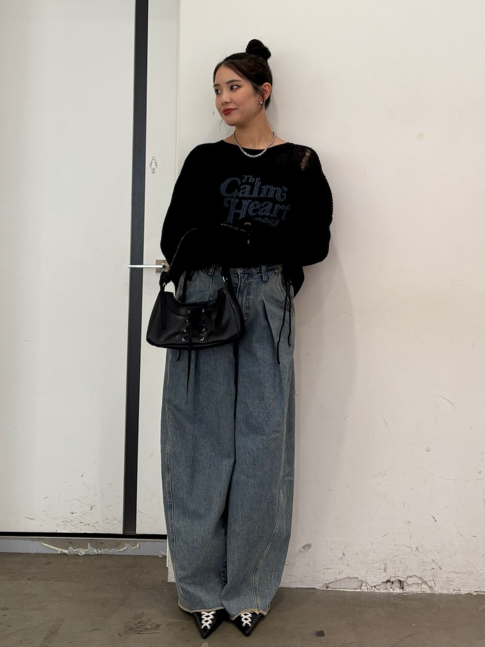 ブラック系のニット/セーター、ブルー系のデニムパンツ、ブラック系のハンドバッグを着用したレディースの秋コーディネートの2枚目の写真