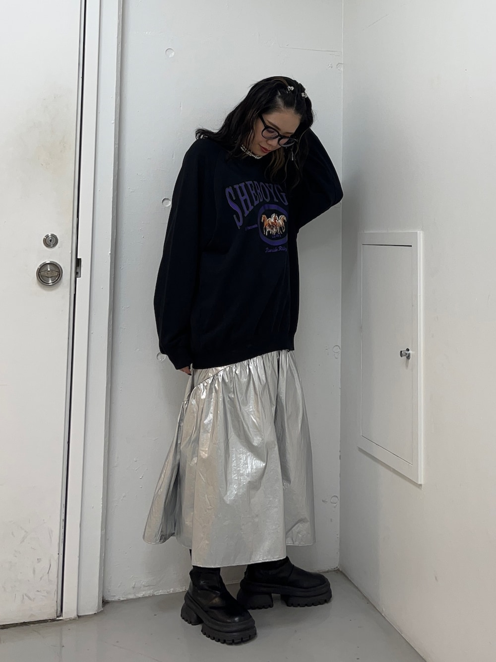 ブラック系のスウェット、シルバー系のスカート、ブラック系のブーツを着用したレディースの冬コーディネートの3枚目の写真