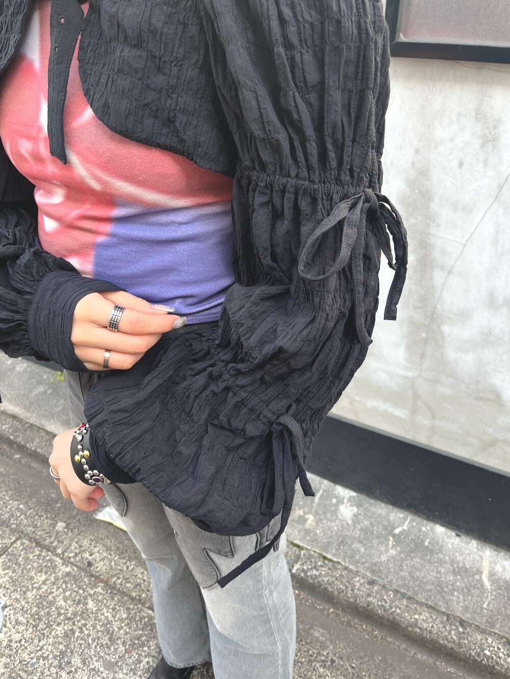 ブラック系のデニムパンツ、ブラック系のカーディガン/ボレロ、パープル系のTシャツ/カットソーを着用したレディースの春コーディネートの6枚目の写真