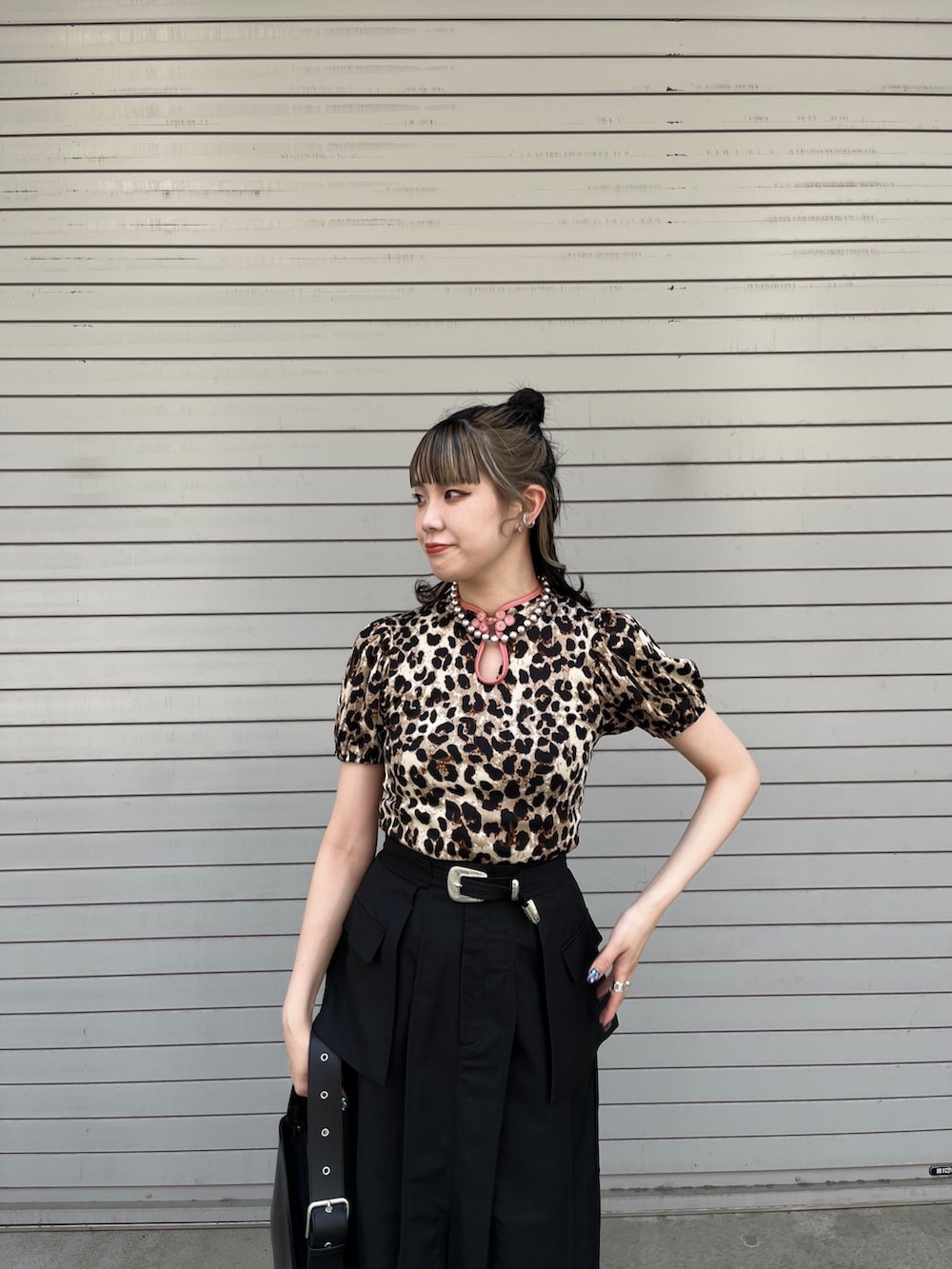 ブラック系のスカート、ブラック系のハンドバッグ、ベージュ系のTシャツ/カットソーを着用したレディースの春コーディネートの4枚目の写真