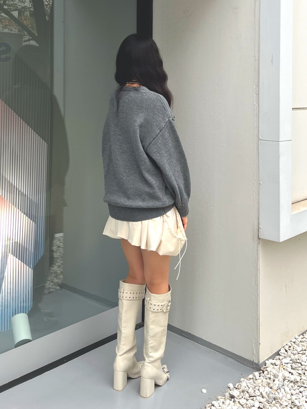グレー系のニット/セーター、ホワイト系のスカート、ホワイト系のブーツを着用したレディースの冬コーディネートの3枚目の写真