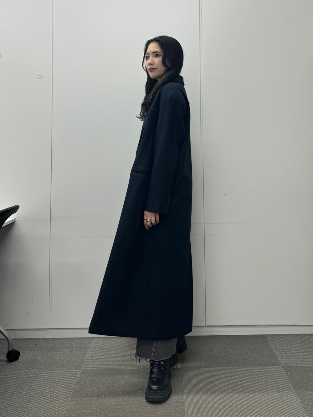 グレー系のワンピース、ブルー系のチェスターコート、ブラック系のデニムパンツを着用したレディースの秋コーディネートの3枚目の写真