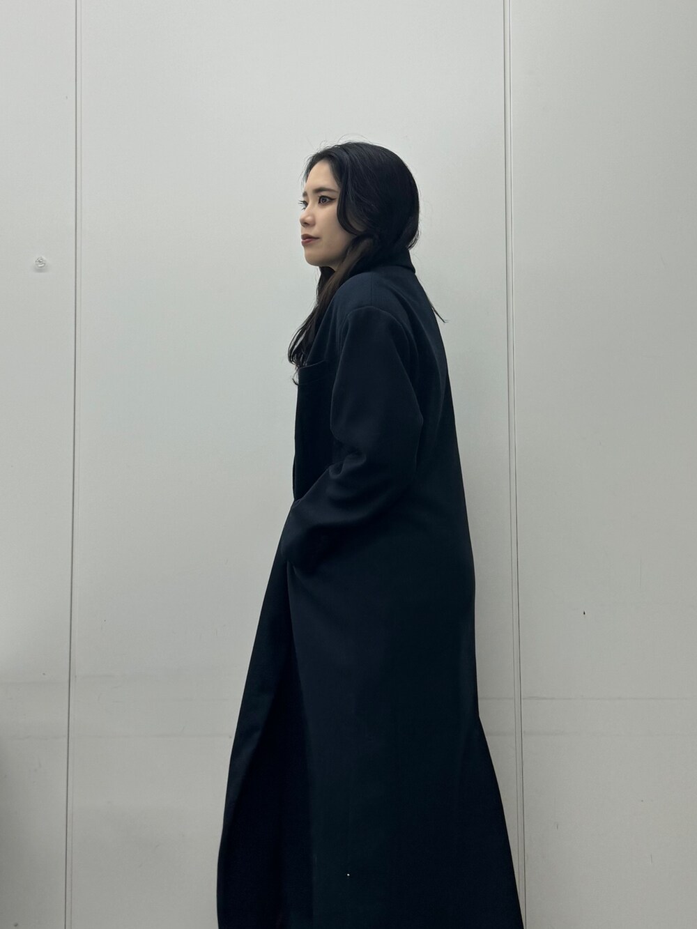 グレー系のワンピース、ブルー系のチェスターコート、ブラック系のデニムパンツを着用したレディースの秋コーディネートの6枚目の写真