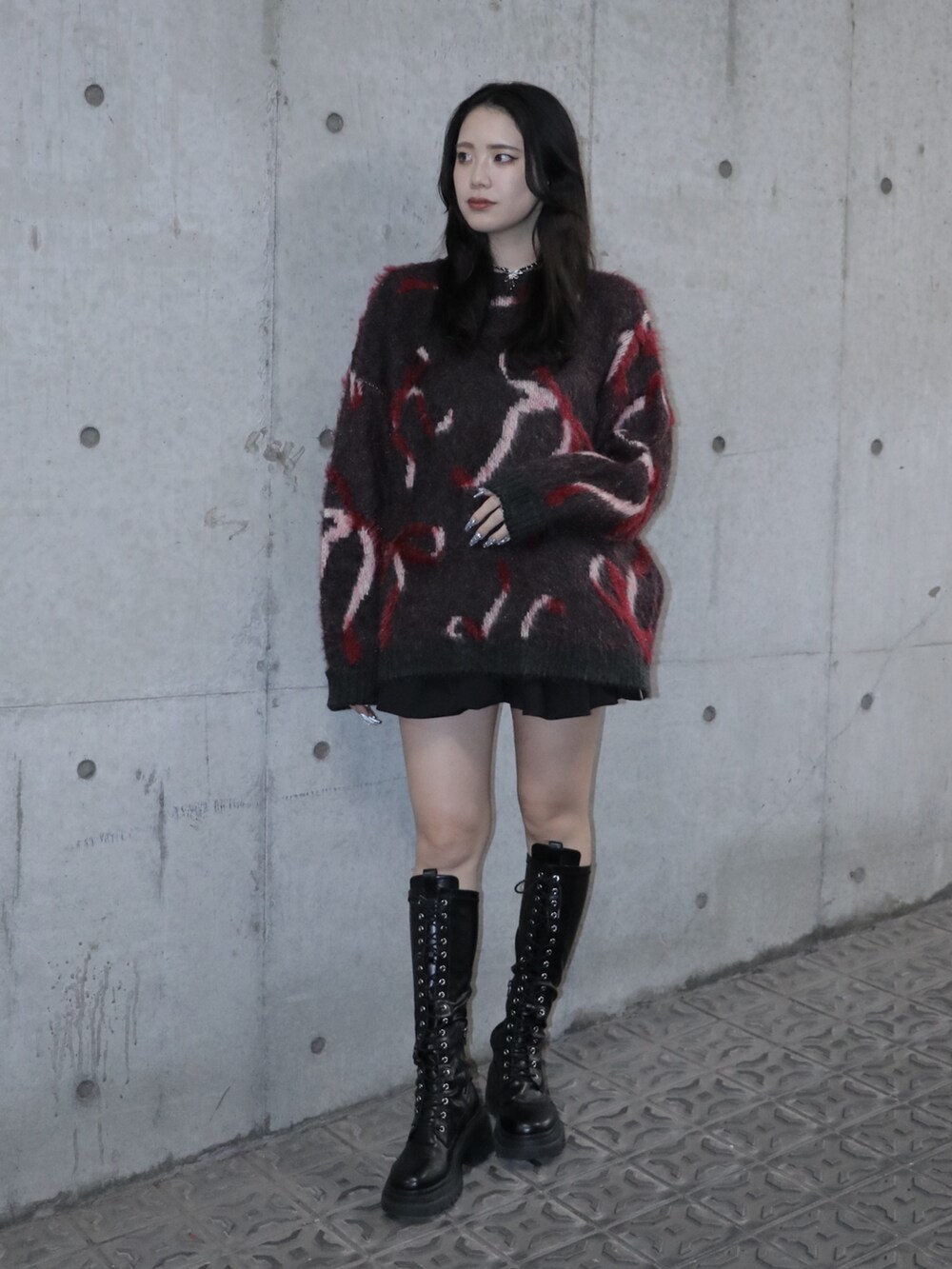 ブラック系のニット/セーター、ブラック系のスカート、ブラック系のブーツを着用したレディースの秋コーディネートの2枚目の写真