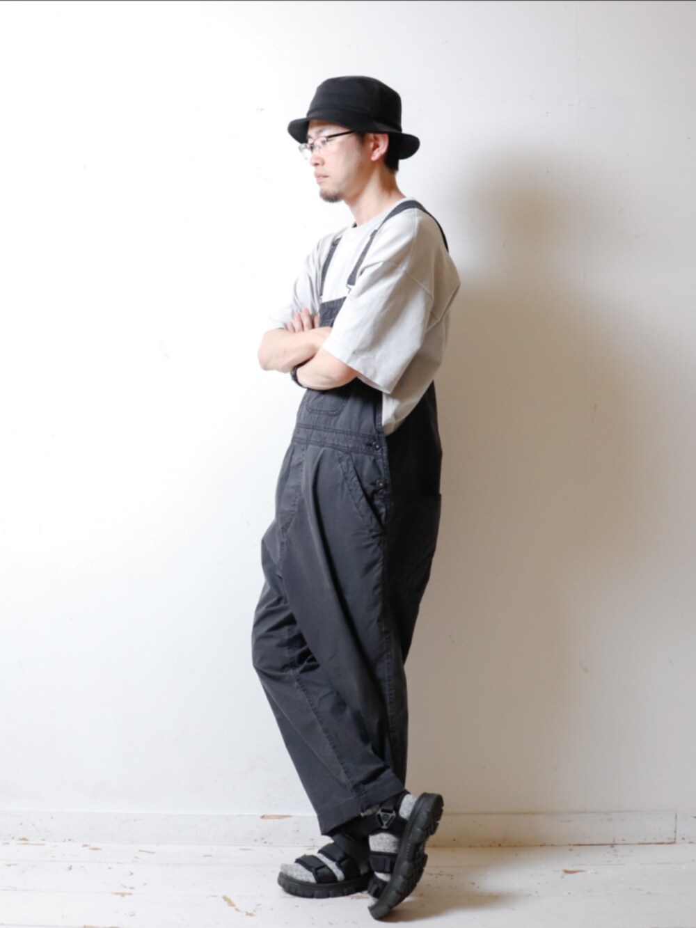 グレー系のTシャツ/カットソー、ブラック系のサロペット/オーバーオール、ブラック系のサンダルを着用したメンズの夏コーディネートの2枚目の写真