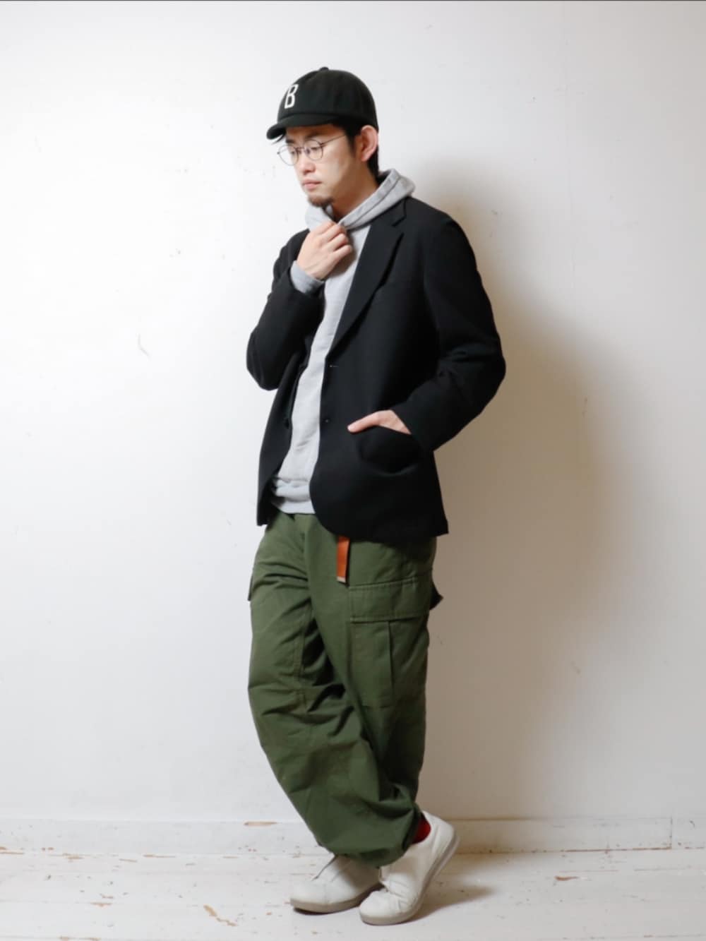 グレー系のパーカー、ブラック系のテーラードジャケット、グリーン系のカーゴパンツを着用したメンズの秋コーディネートの2枚目の写真