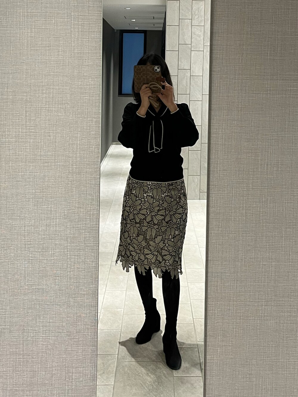 グレー系のスカート、ブラック系のニット/セーター、ブラック系のブーツを着用したレディースの春コーディネートの3枚目の写真