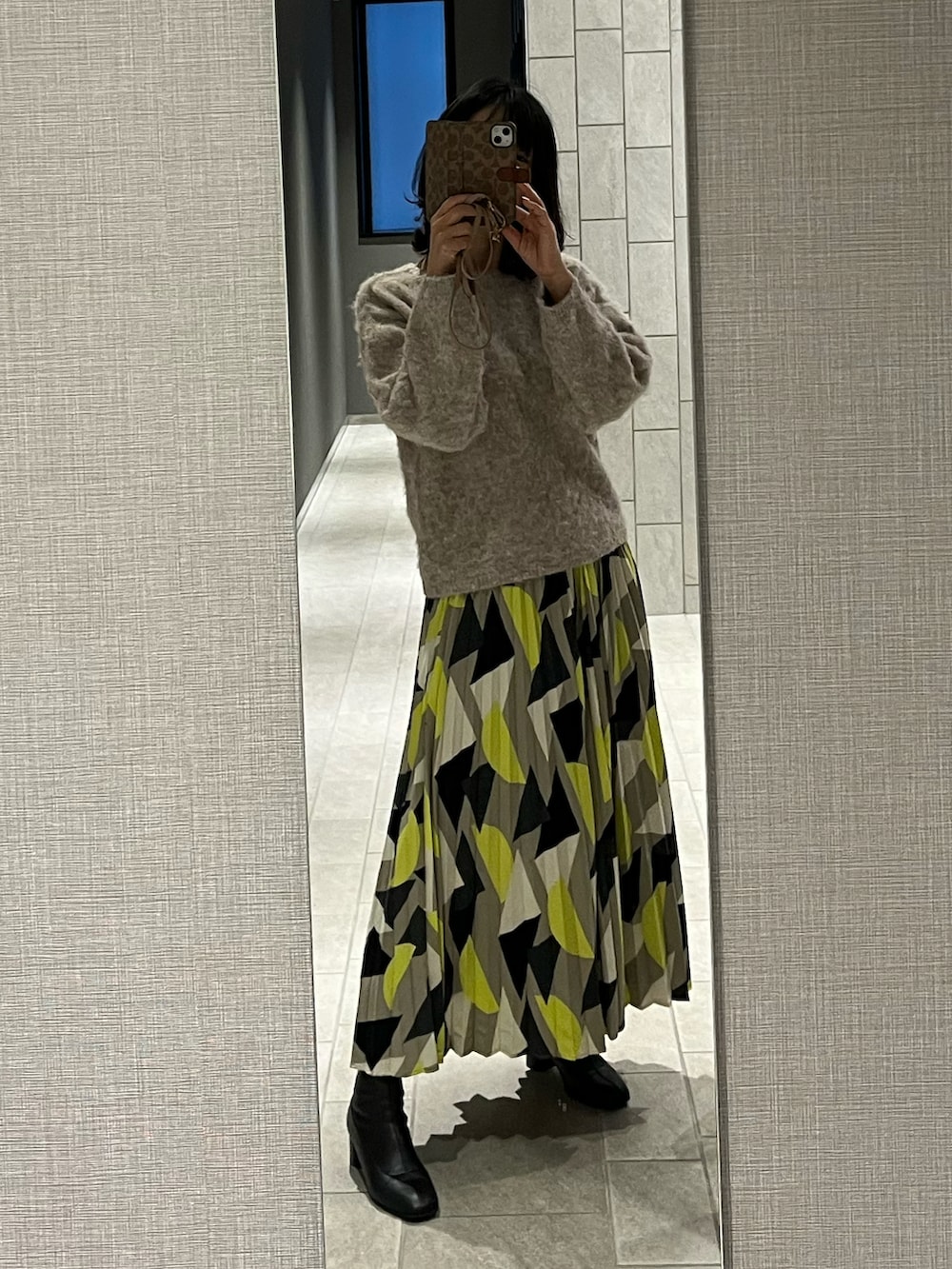 イエロー系のスカート、ブラック系のブーツ、ブルー系のニット/セーターを着用したレディースの冬コーディネートの2枚目の写真