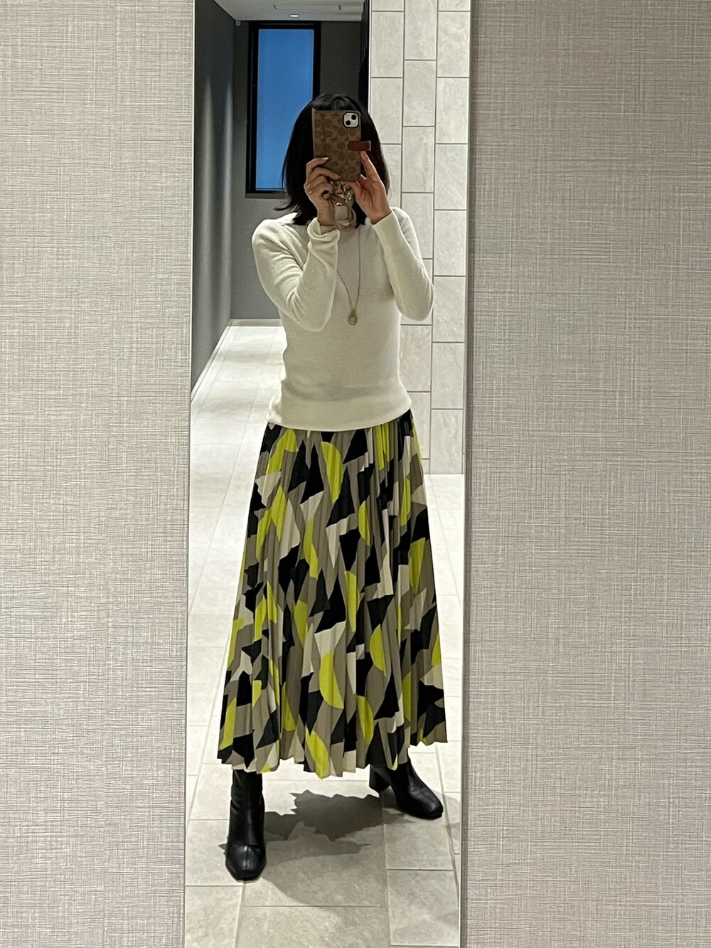 イエロー系のスカート、ホワイト系のニット/セーター、グレー系のカーディガン/ボレロを着用したレディースの冬コーディネートの3枚目の写真