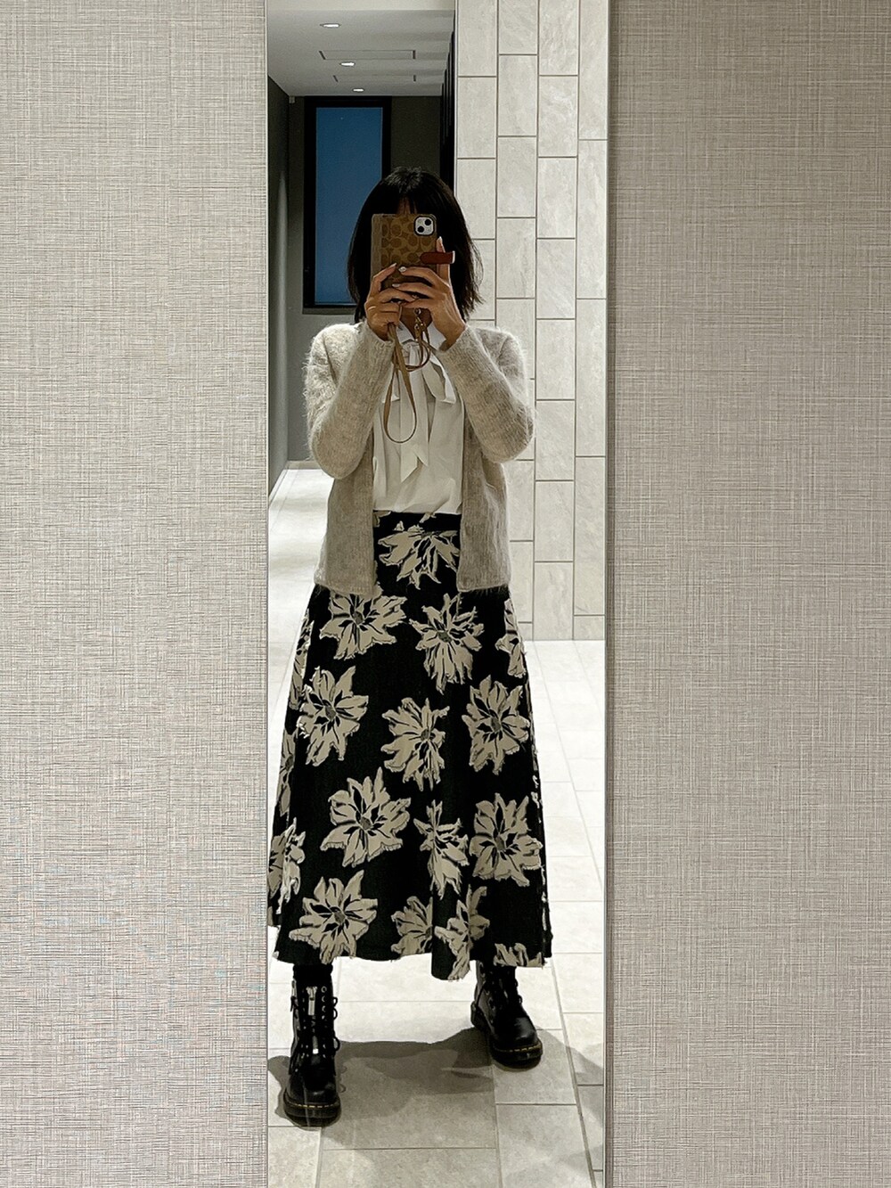 ブラック系のスカート、ブラック系のブーツ、シルバー系のトップスを着用したレディースの冬コーディネートの2枚目の写真