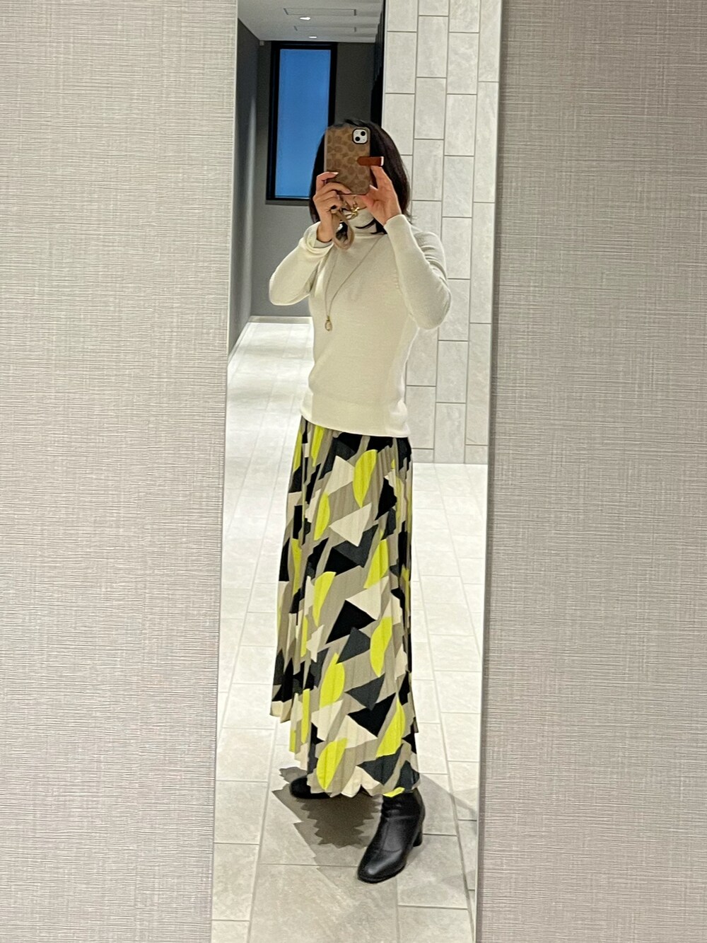 イエロー系のスカート、ホワイト系のニット/セーター、グレー系のカーディガン/ボレロを着用したレディースの冬コーディネートの4枚目の写真