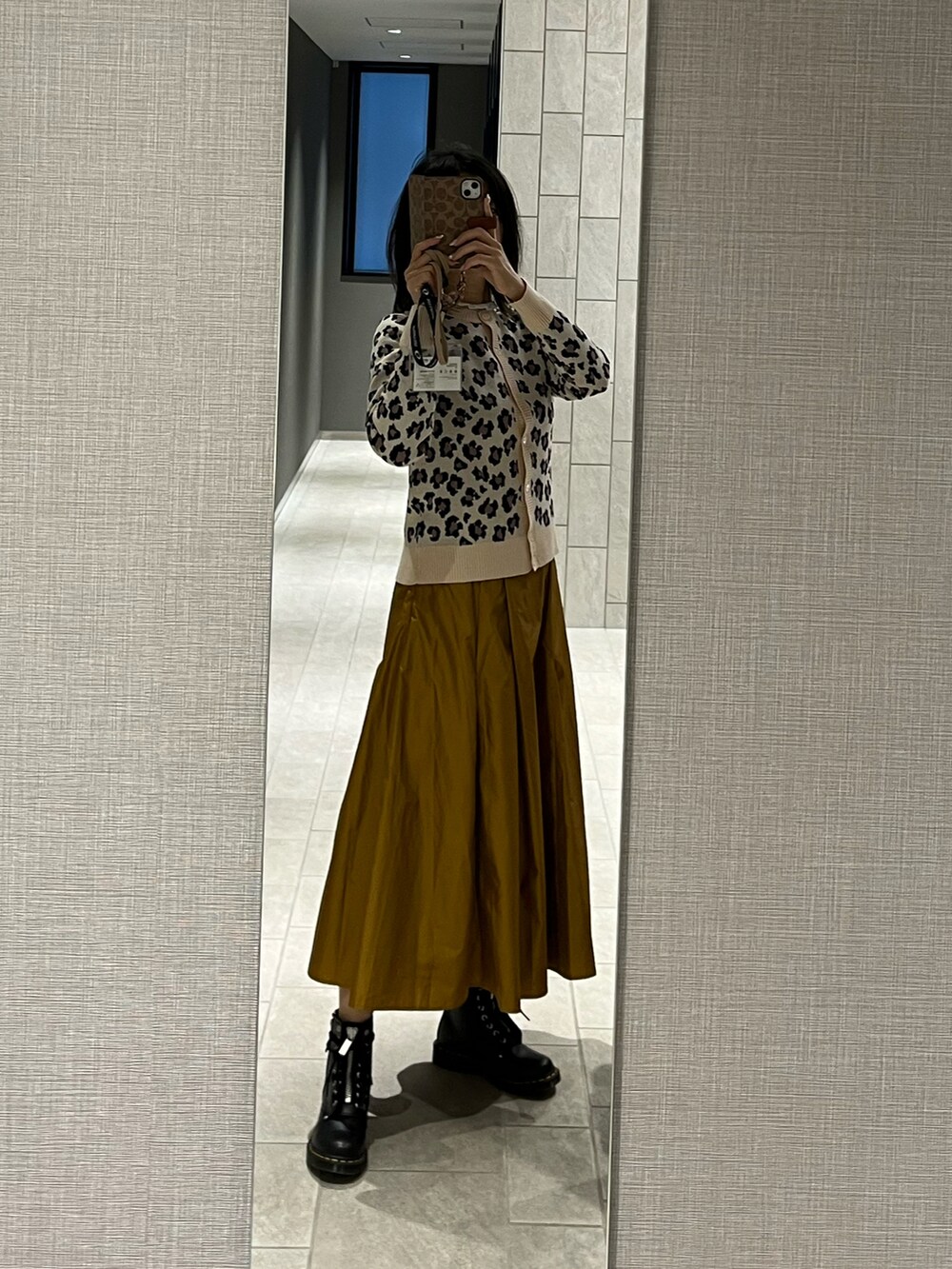ブラック系のブーツ、イエロー系のスカート、ベージュ系のカーディガン/ボレロを着用したレディースの冬コーディネートの2枚目の写真
