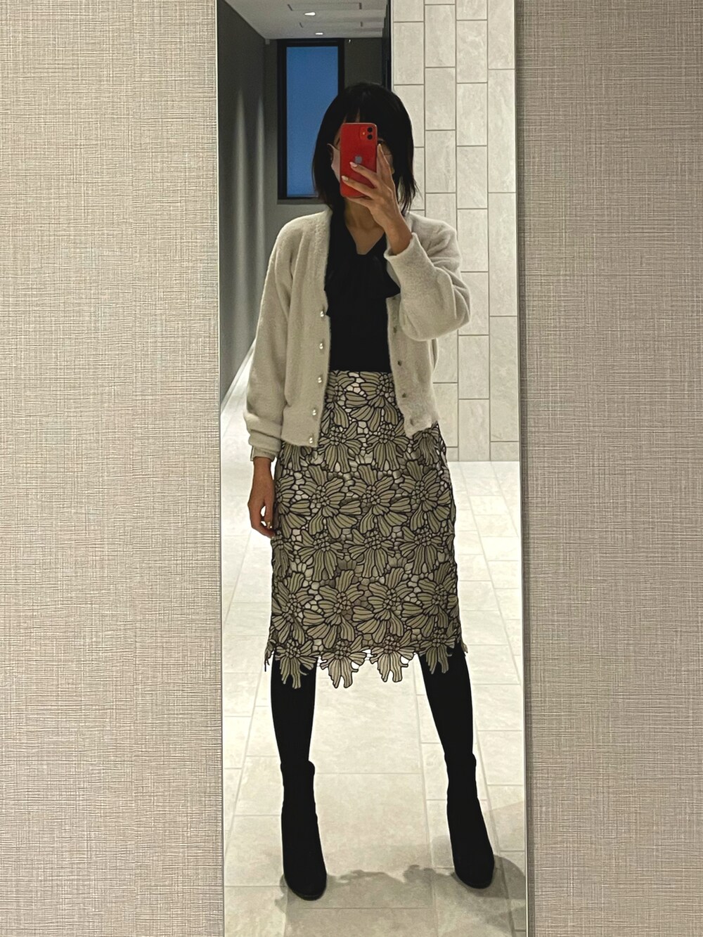 グレー系のスカート、ブラック系のブーツ、グレー系のカーディガン/ボレロを着用したレディースの冬コーディネートの2枚目の写真