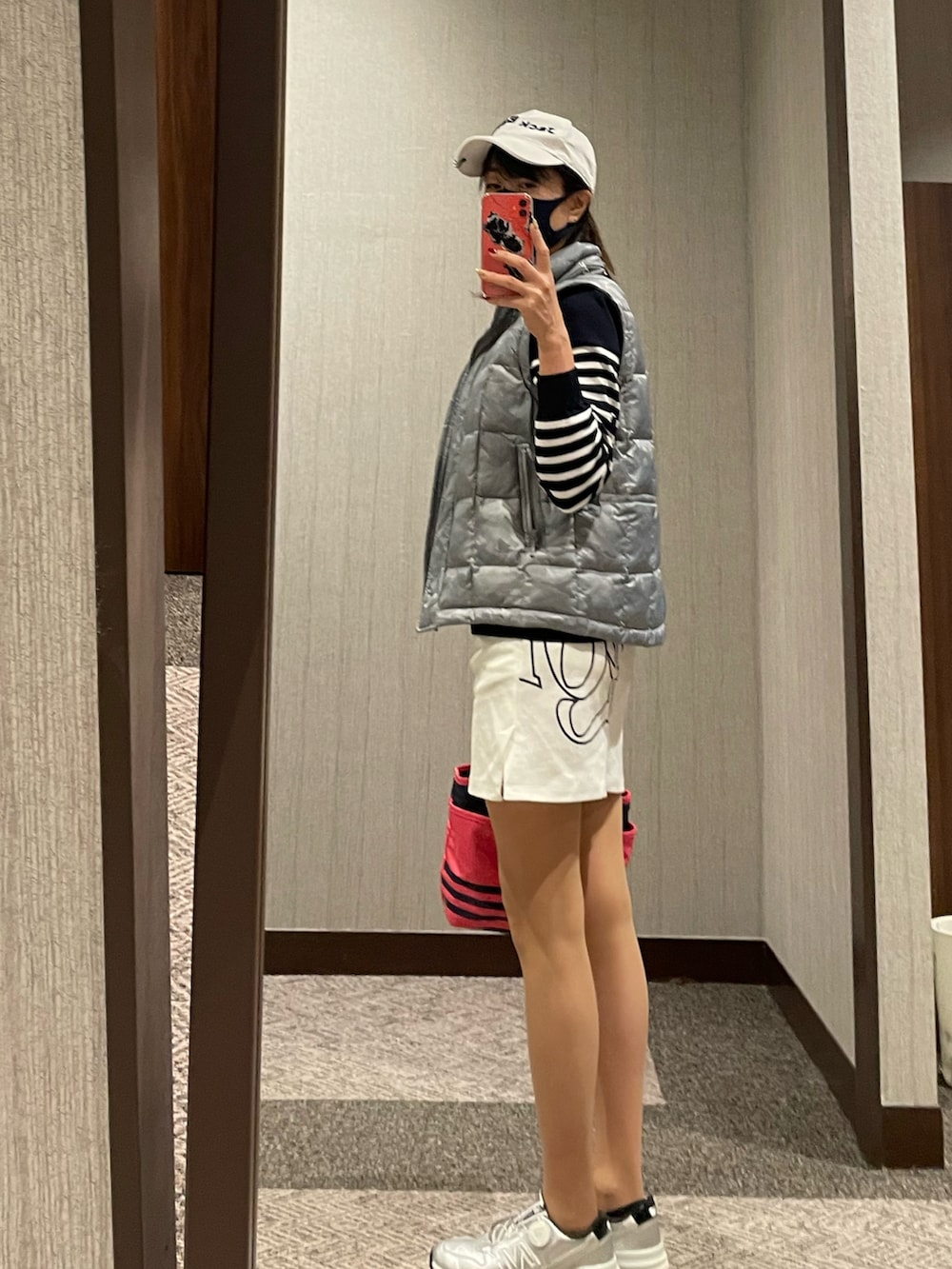 ピンク系のバッグ、シルバー系のシューズ、ホワイト系のスカートを着用したレディースの秋コーディネートの2枚目の写真