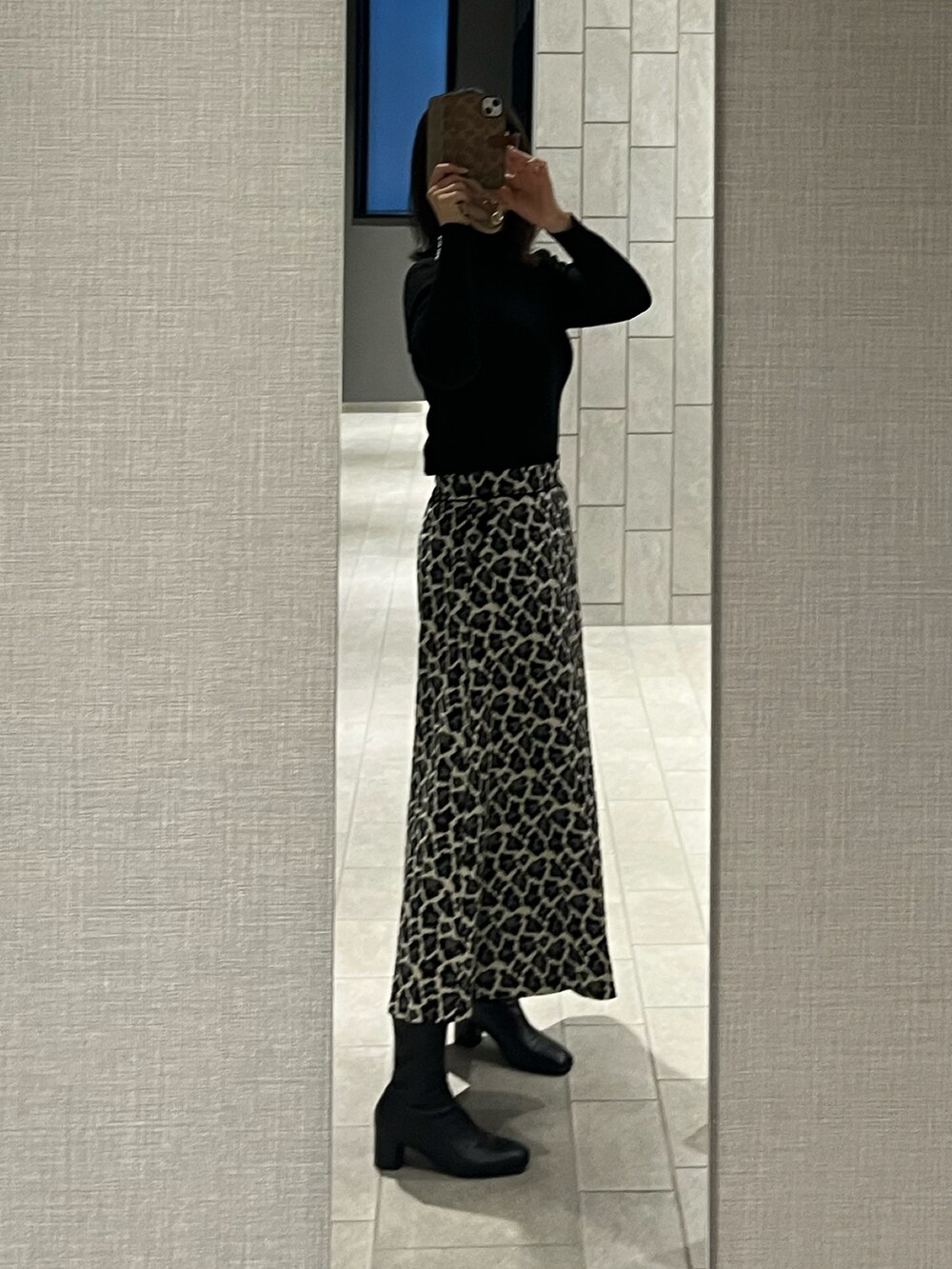 ホワイト系のスカート、ブラック系のニット/セーター、ブラック系のブーツを着用したレディースの冬コーディネートの2枚目の写真