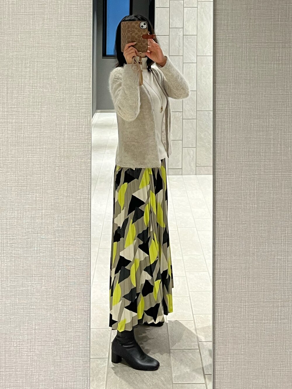 イエロー系のスカート、ホワイト系のニット/セーター、グレー系のカーディガン/ボレロを着用したレディースの冬コーディネートの2枚目の写真