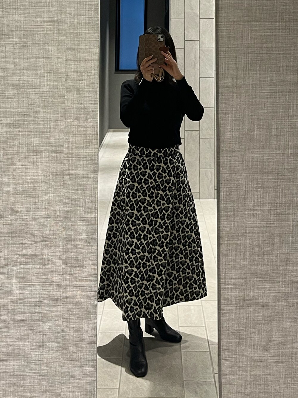 ホワイト系のスカート、ブラック系のニット/セーター、ブラック系のブーツを着用したレディースの冬コーディネートの3枚目の写真