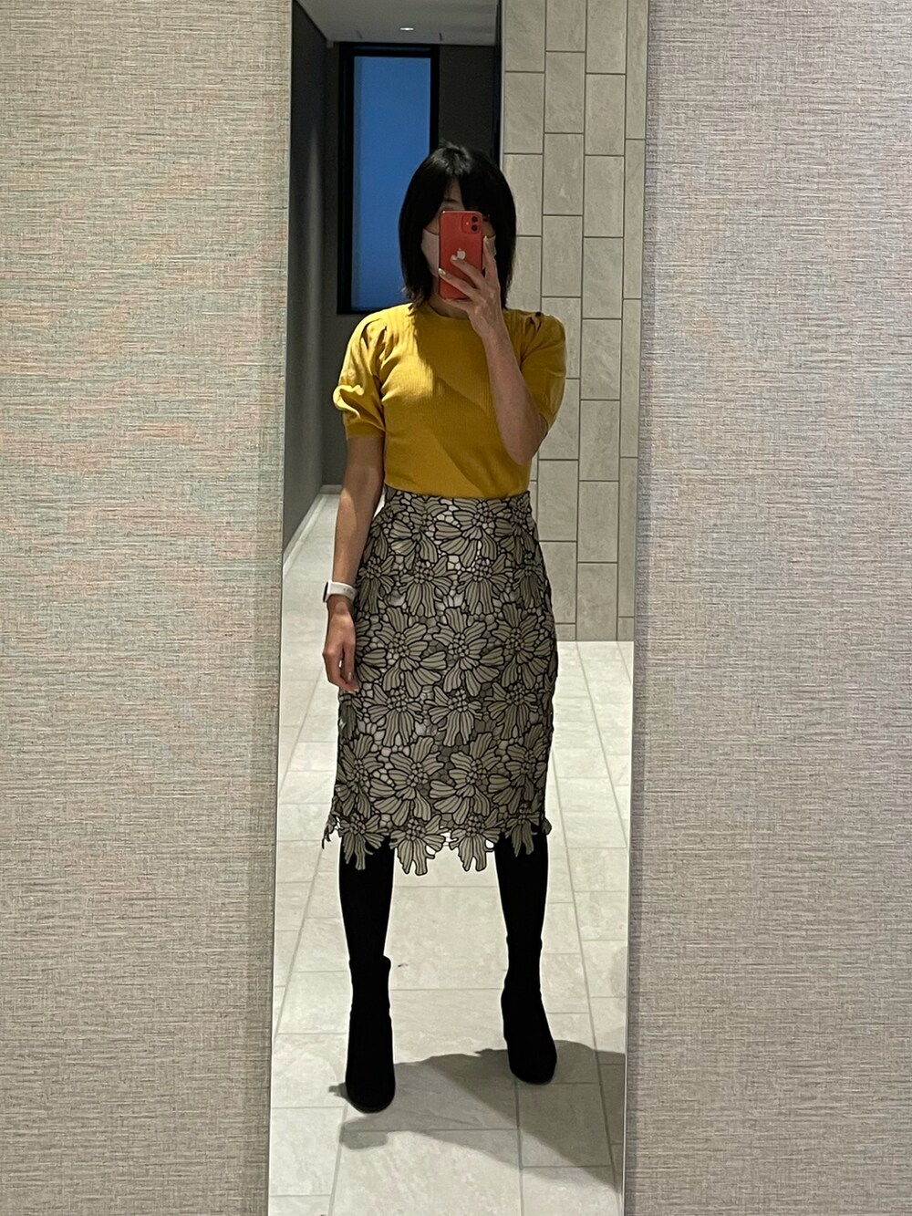 グレー系のスカート、ブラック系のブーツ、イエロー系のニット/セーターを着用したレディースの春コーディネートの2枚目の写真