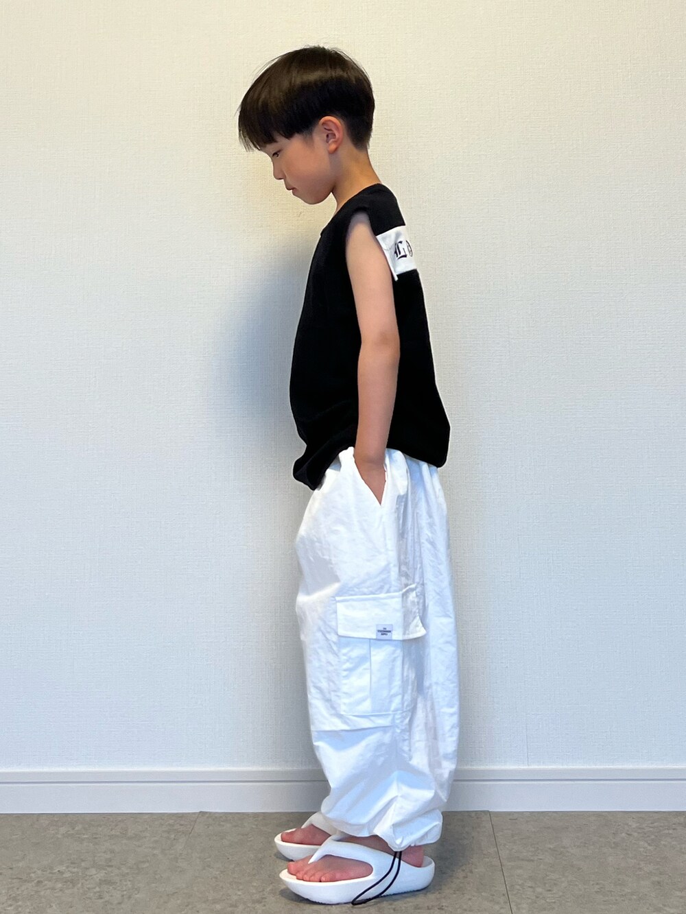 ホワイト系のカーゴパンツ、ブラック系のタンクトップ、ホワイト系のサンダルを着用したキッズの夏コーディネートの5枚目の写真
