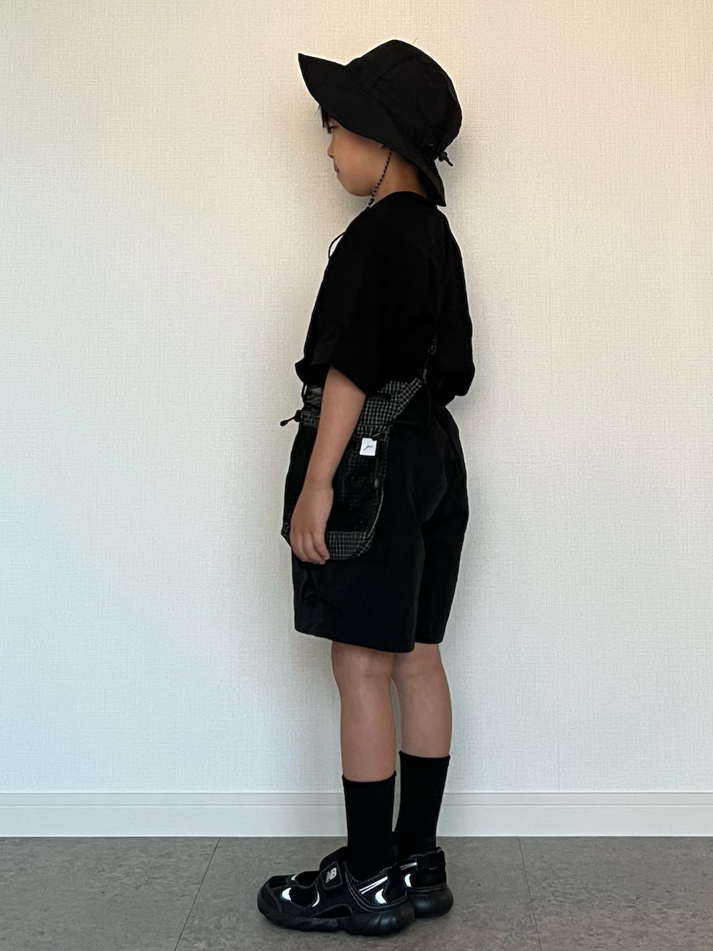 ブラック系のショルダーバッグ、ブラック系のパンツ、ブラック系のサンダルを着用したキッズの夏コーディネートの2枚目の写真