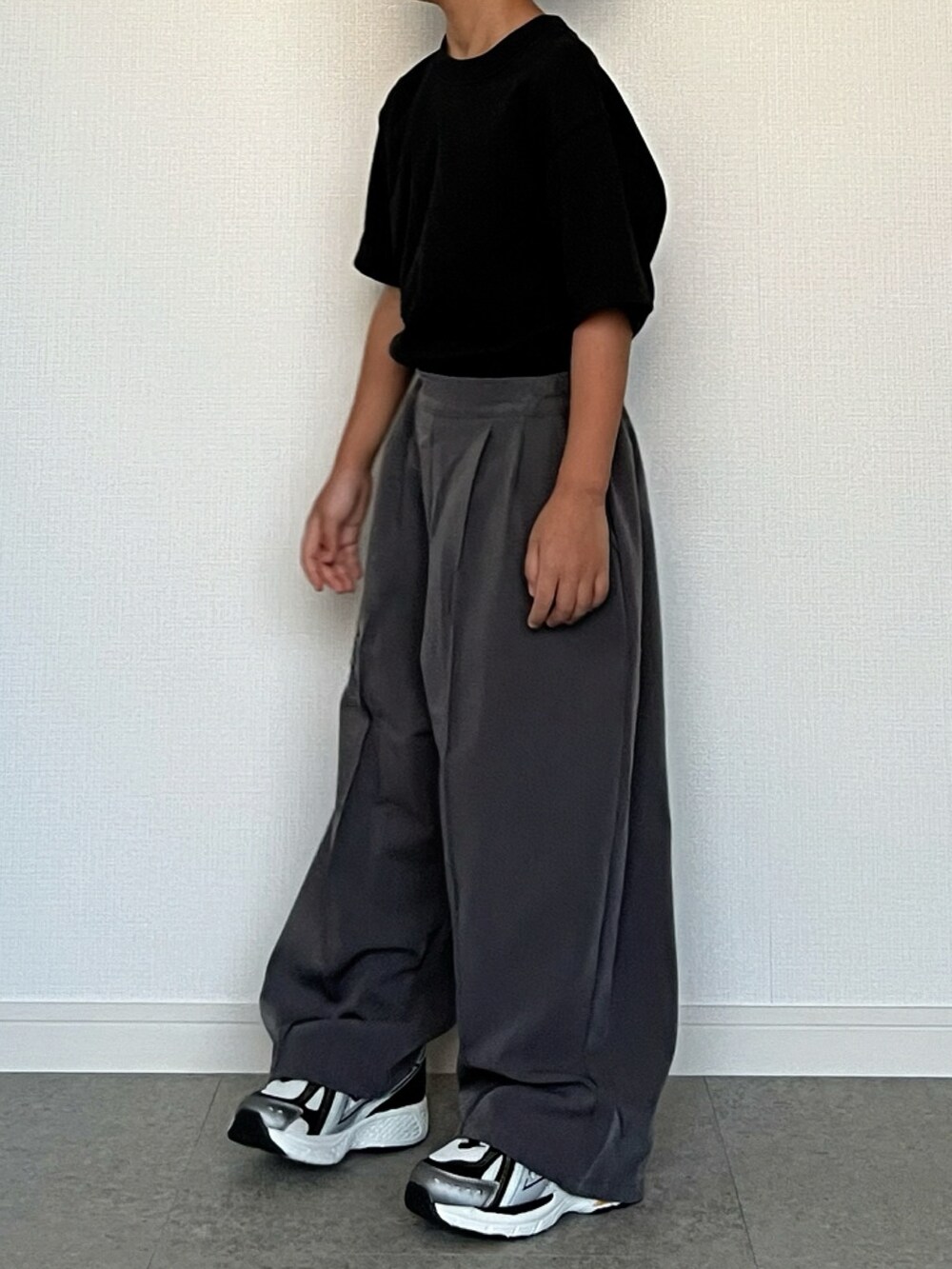 ブラック系のTシャツ/カットソー、グレー系のスラックス、ホワイト系のスニーカーを着用したキッズの秋コーディネートの2枚目の写真