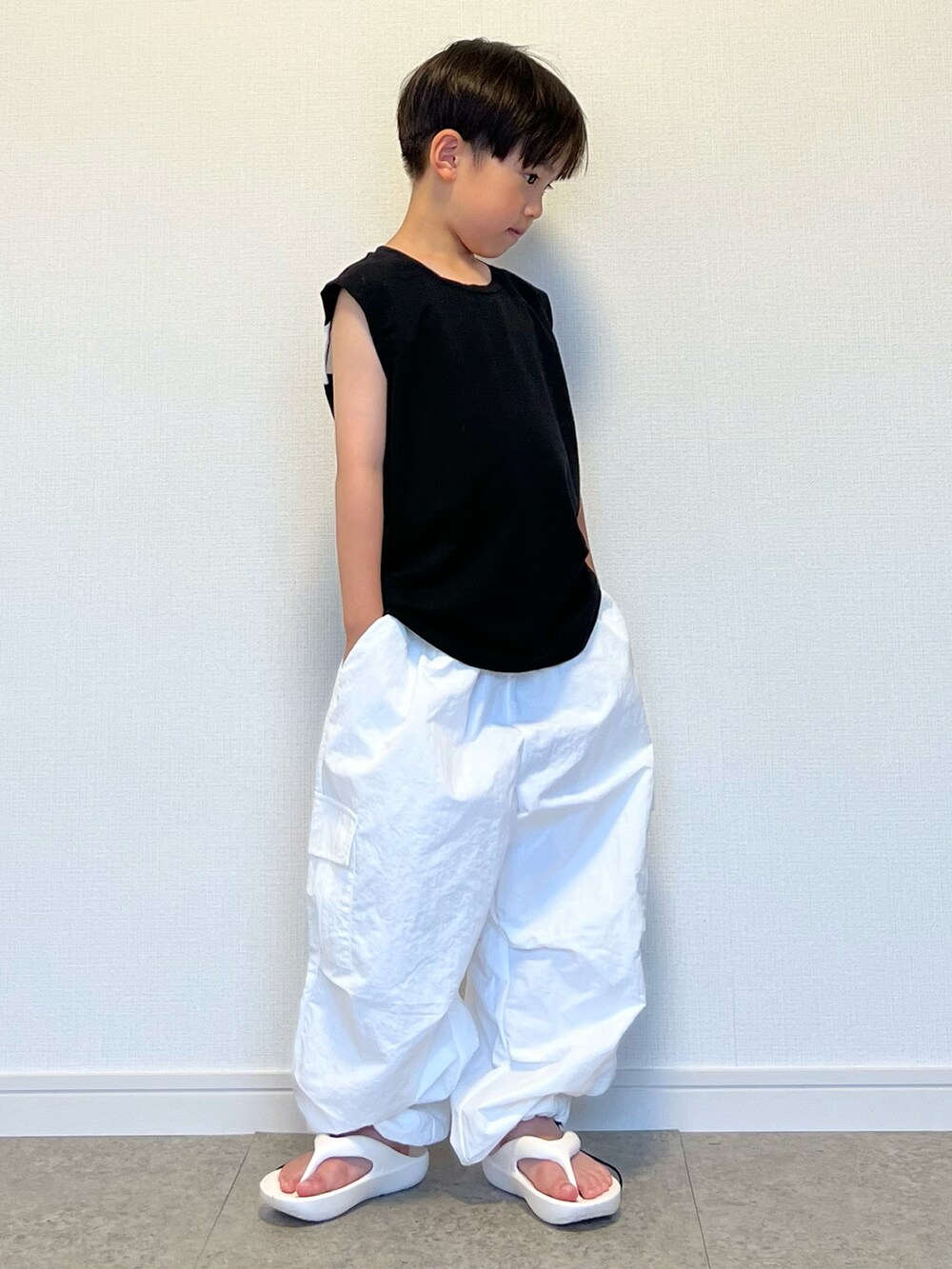 ホワイト系のカーゴパンツ、ブラック系のタンクトップ、ホワイト系のサンダルを着用したキッズの夏コーディネートの2枚目の写真