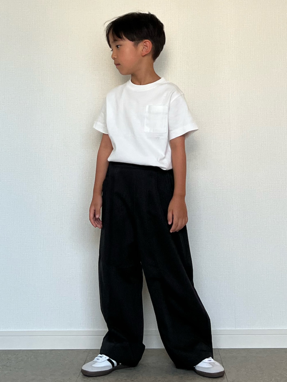 ブラック系のスラックス、ホワイト系のスニーカー、ホワイト系のTシャツ/カットソーを着用したキッズの夏コーディネートの2枚目の写真